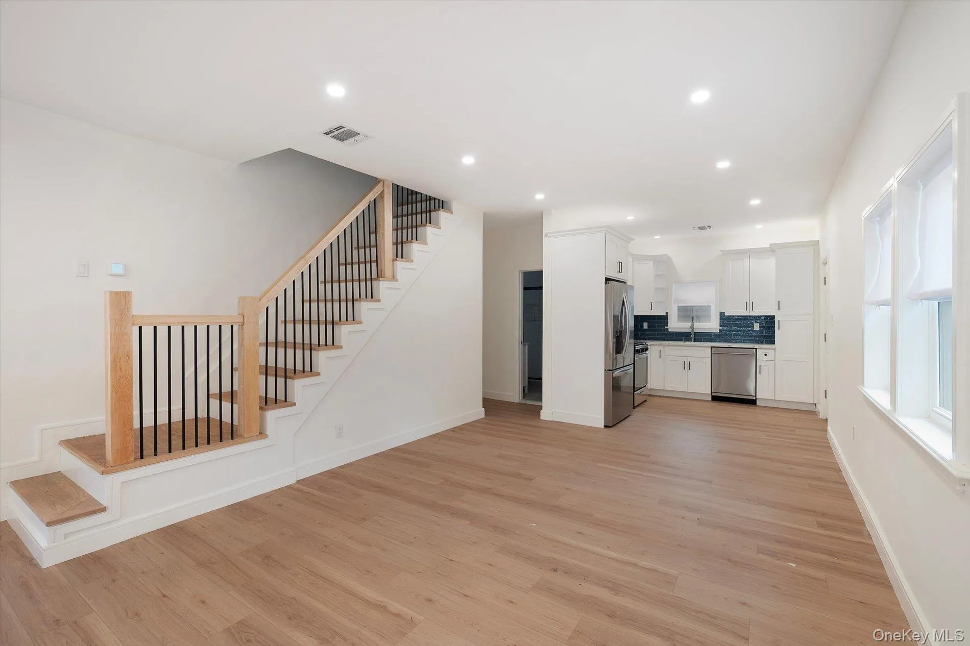 Kitchen with white cabinets, light wood-style floors, recessed lighting, appliances with stainless steel finishes, and decorative backsplash Kitchen with white cabinets, light wood-style floors, recessed lighting, appliances with stainless steel finishes, and decorative backsplash