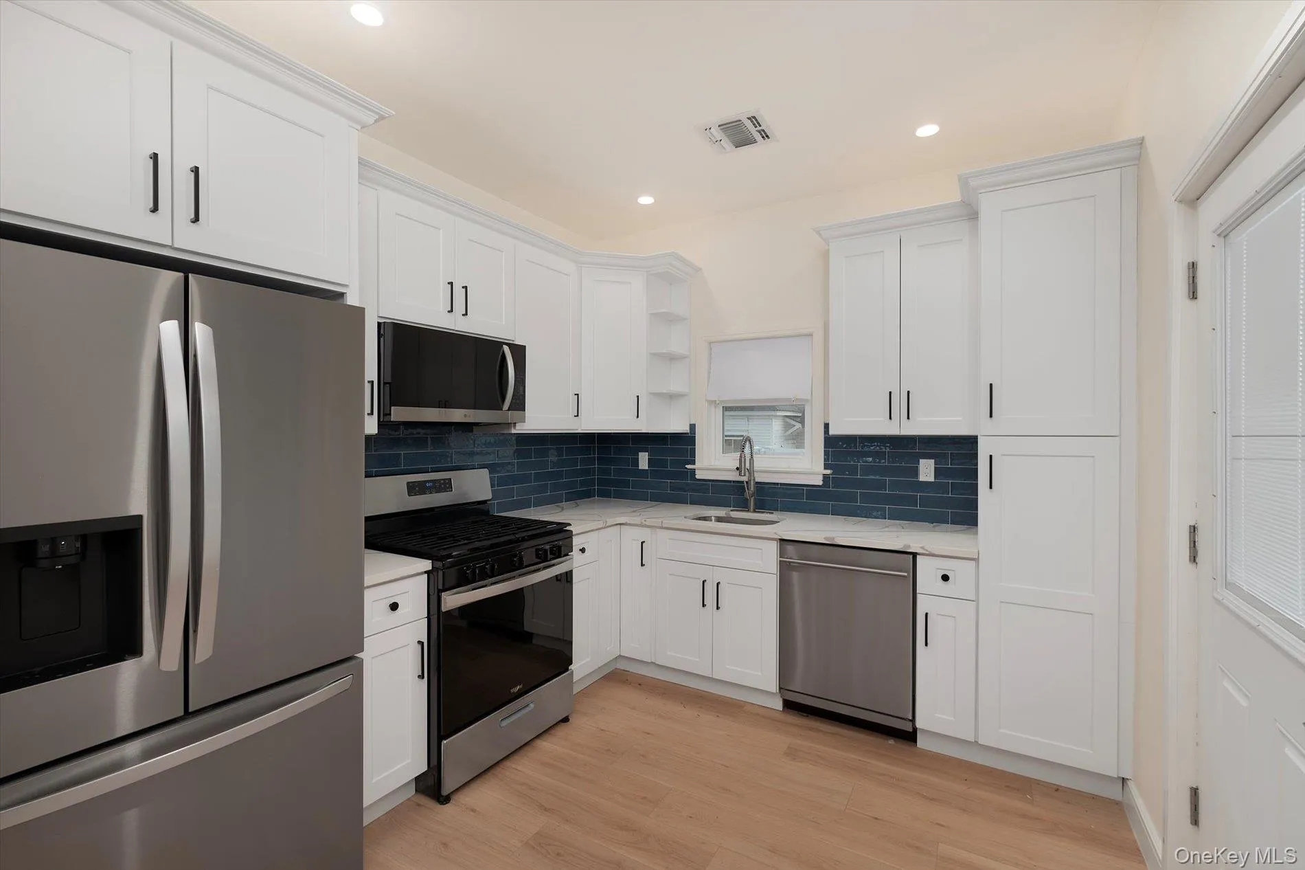 Kitchen with appliances with stainless steel finishes, open shelves, white cabinets, recessed lighting, and light wood-type flooring Kitchen with appliances with stainless steel finishes, open shelves, white cabinets, recessed lighting, and light wood-type flooring