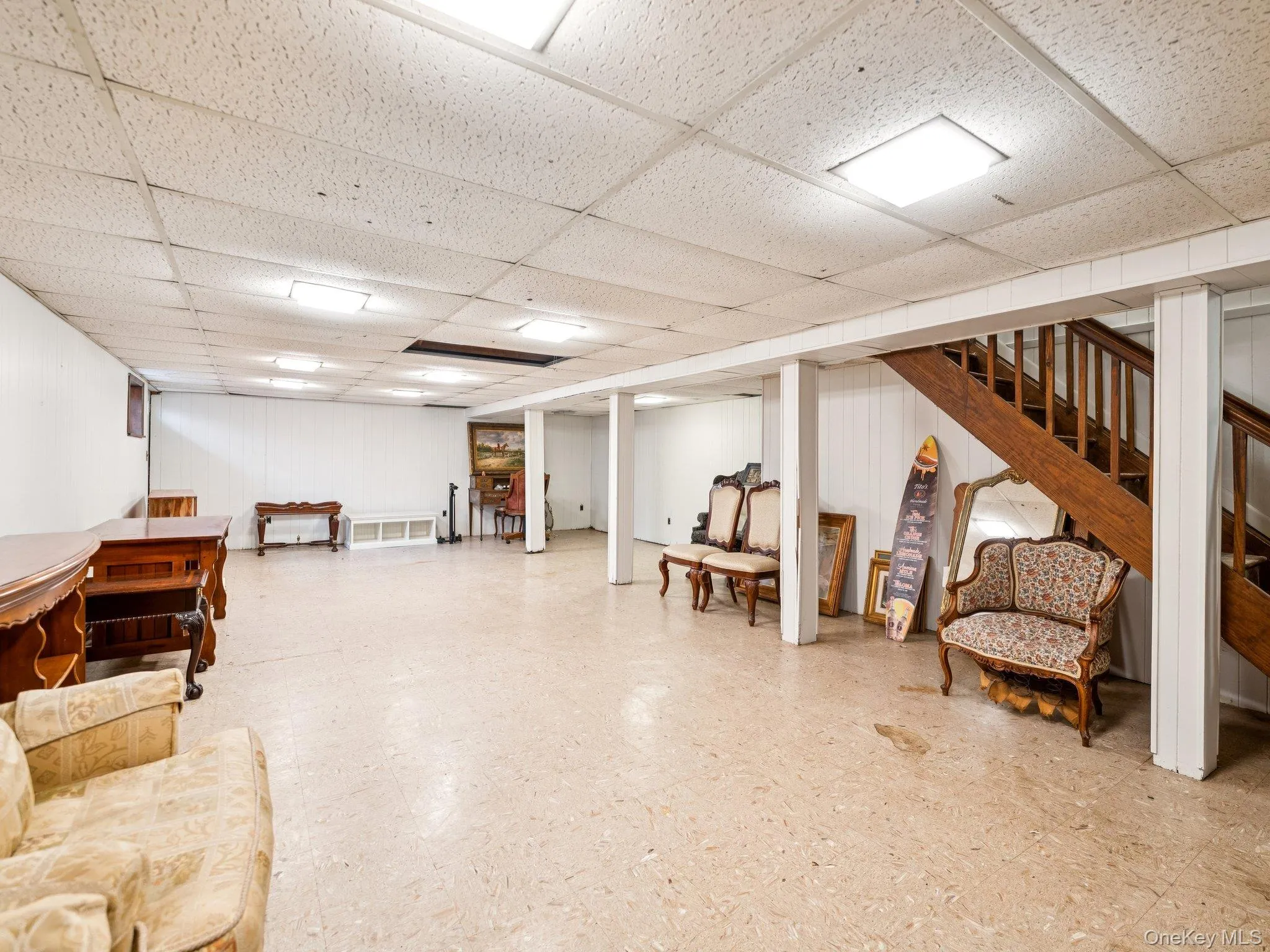 Finished basement with tile patterned floors, stairs, and a paneled ceiling Finished basement with tile patterned floors, stairs, and a paneled ceiling