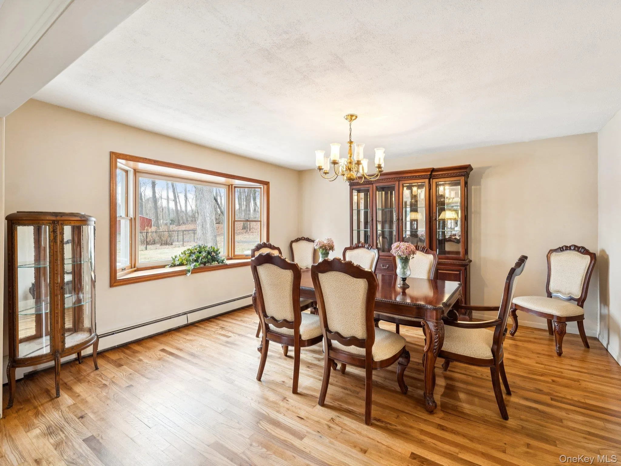 Dining room with a baseboard heating unit, a chandelier, and light wood-type flooring Dining room with a baseboard heating unit, a chandelier, and light wood-type flooring
