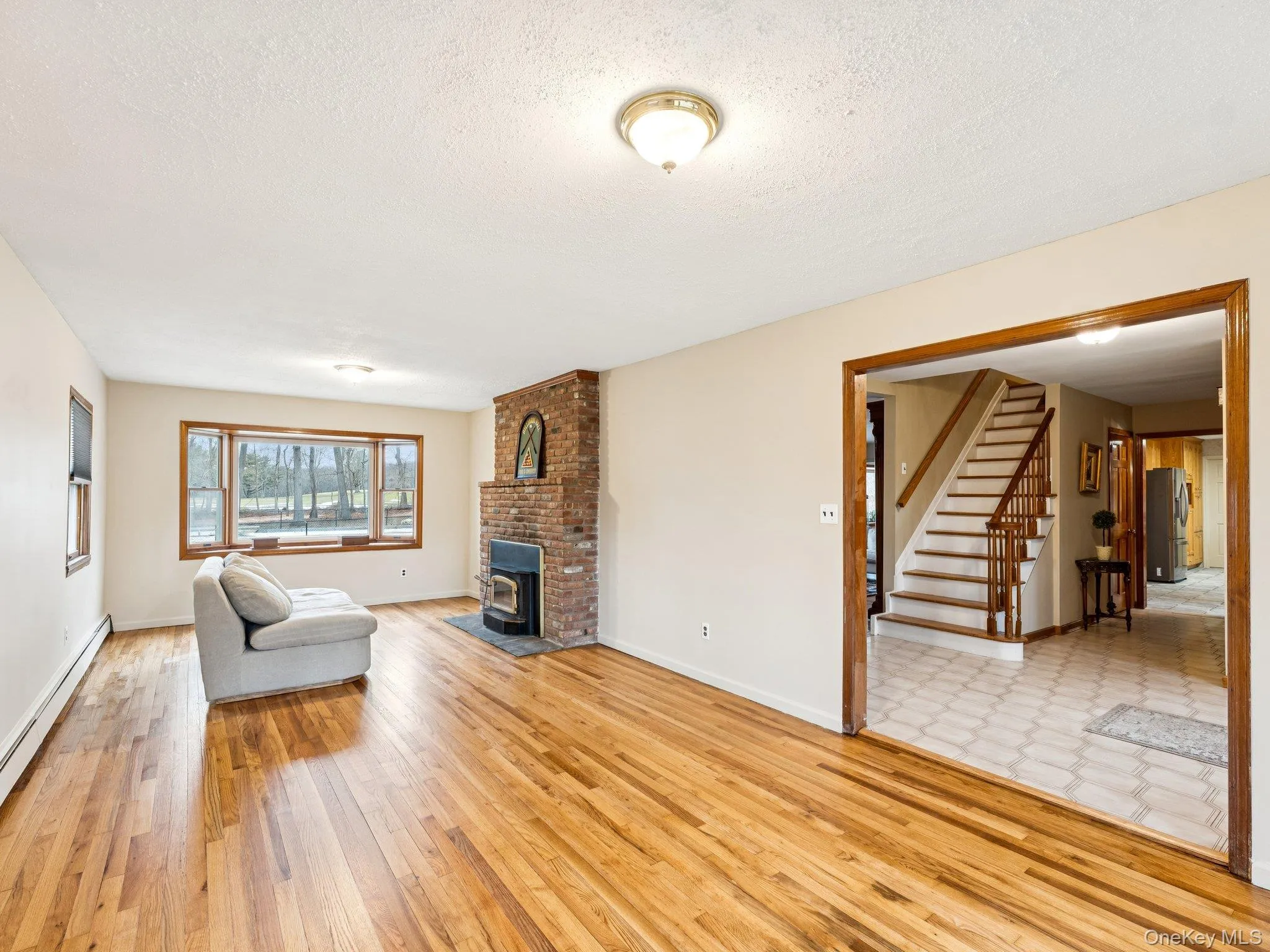 Living area with stairway, a textured ceiling, and light wood-style flooring Living area with stairway, a textured ceiling, and light wood-style flooring