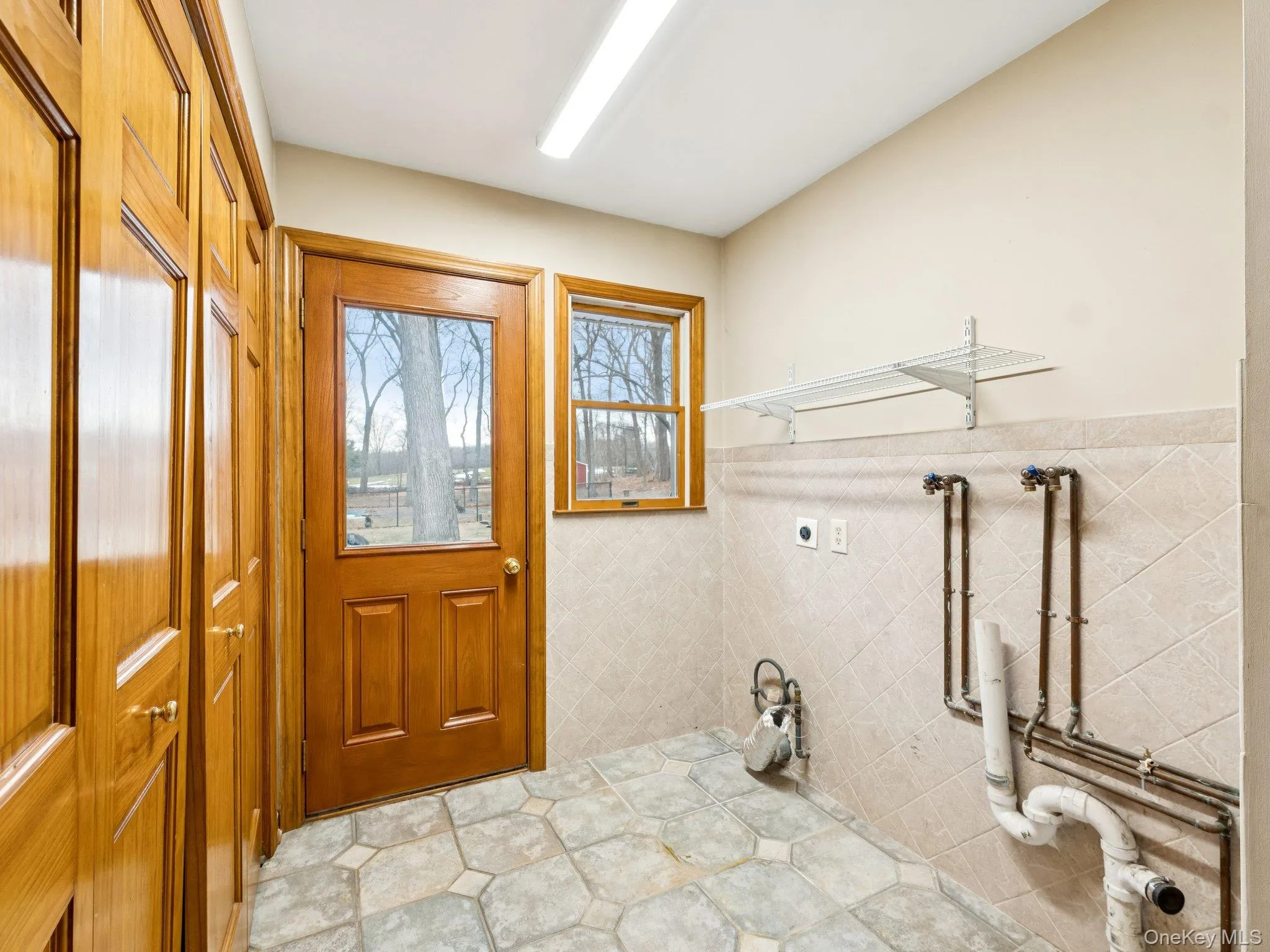 Washroom with hookup for a washing machine, electric dryer hookup, tile walls, and wainscoting Washroom with hookup for a washing machine, electric dryer hookup, tile walls, and wainscoting