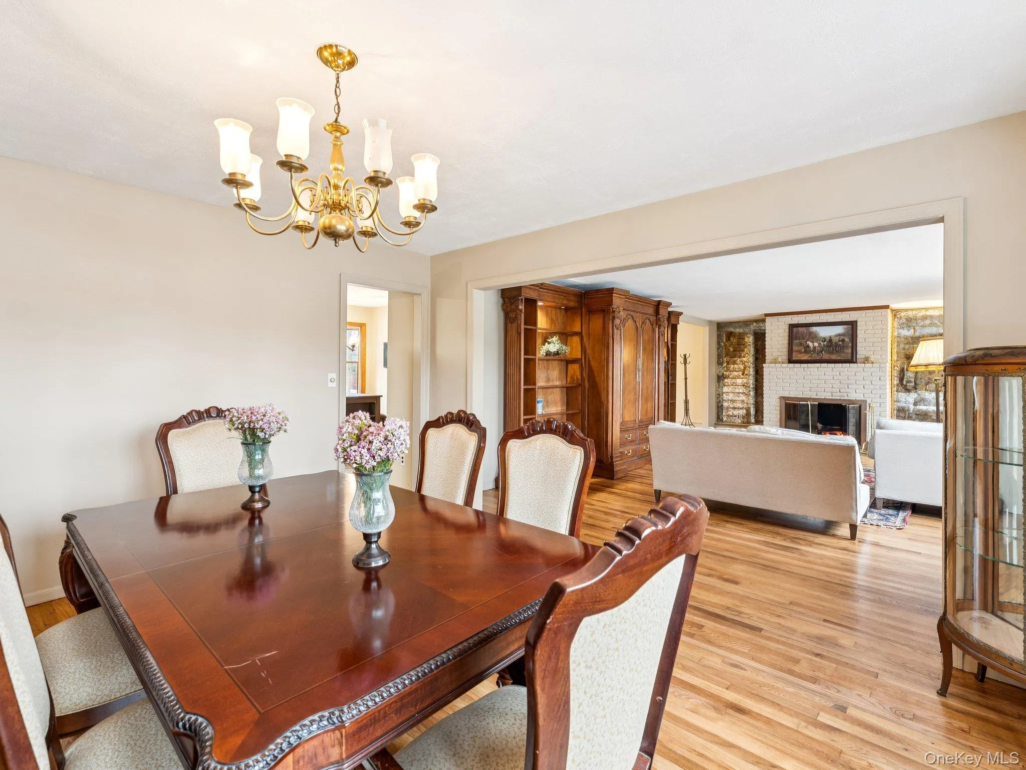 Dining area with light wood-type flooring, a fireplace, and a chandelier Dining area with light wood-type flooring, a fireplace, and a chandelier