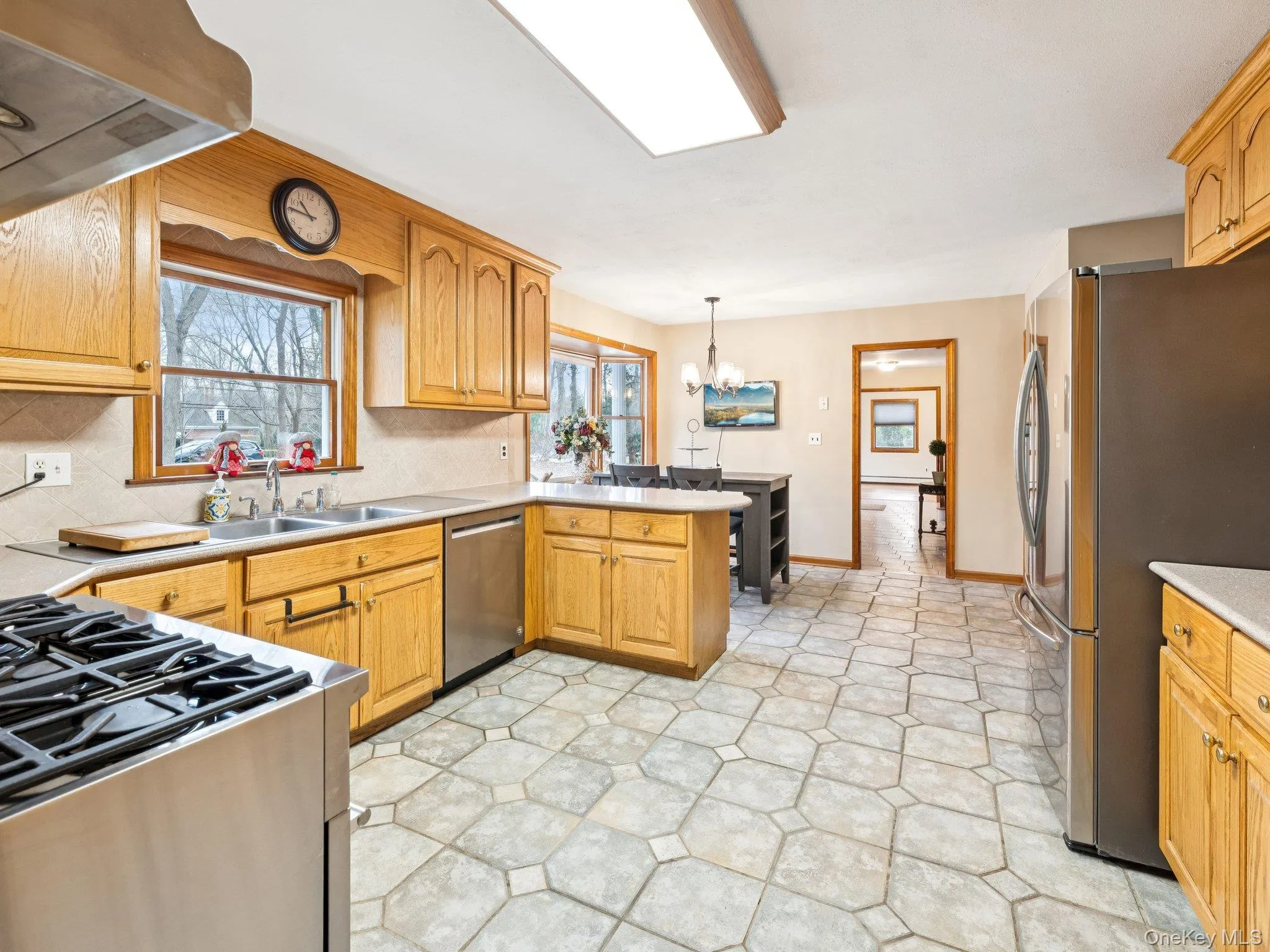 Kitchen with stainless steel appliances, decorative backsplash, a peninsula, light countertops, and ventilation hood Kitchen with stainless steel appliances, decorative backsplash, a peninsula, light countertops, and ventilation hood