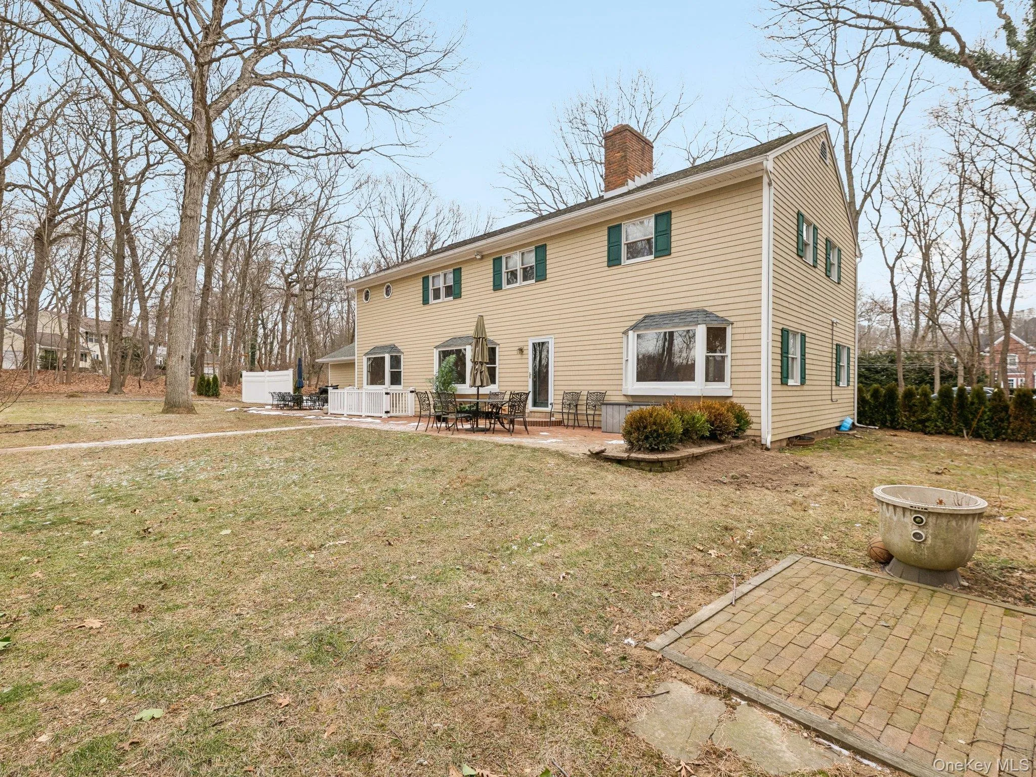 Back of house featuring a chimney, a patio area, and a lawn Back of house featuring a chimney, a patio area, and a lawn