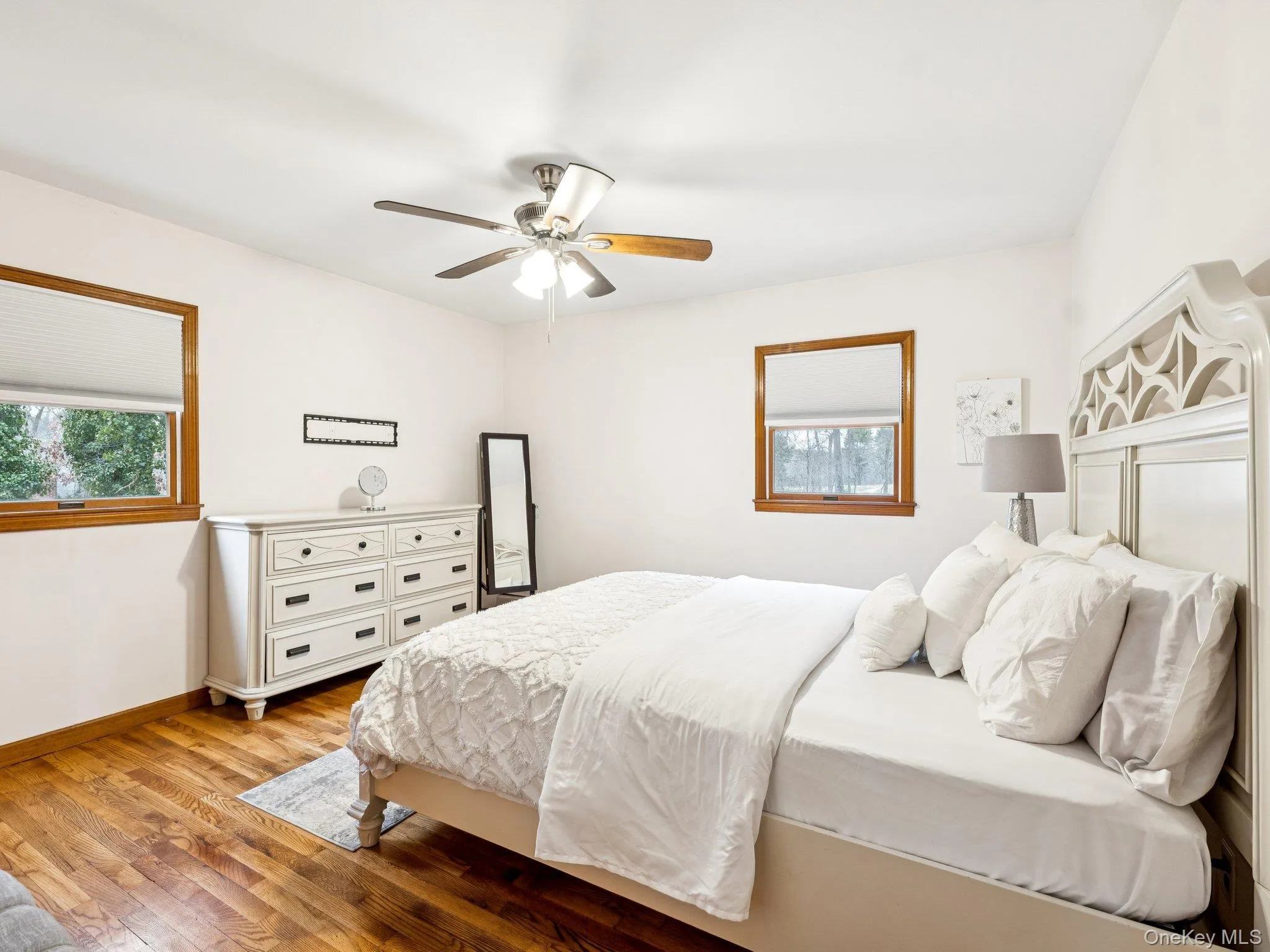 Bedroom featuring light wood-type flooring, multiple windows, and a ceiling fan Bedroom featuring light wood-type flooring, multiple windows, and a ceiling fan