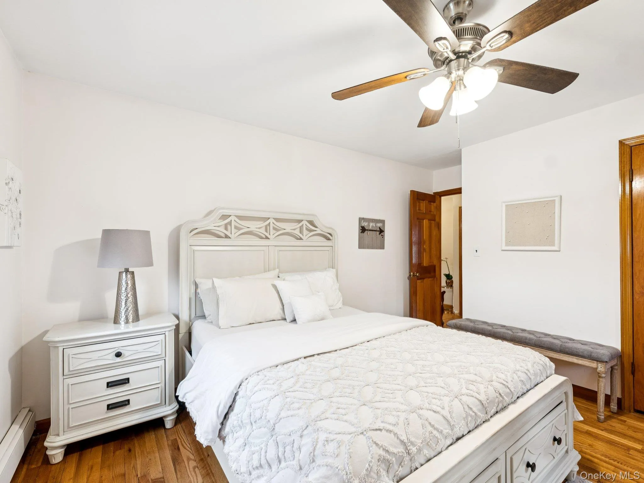 Bedroom with light wood-type flooring, a ceiling fan, and a baseboard radiator Bedroom with light wood-type flooring, a ceiling fan, and a baseboard radiator