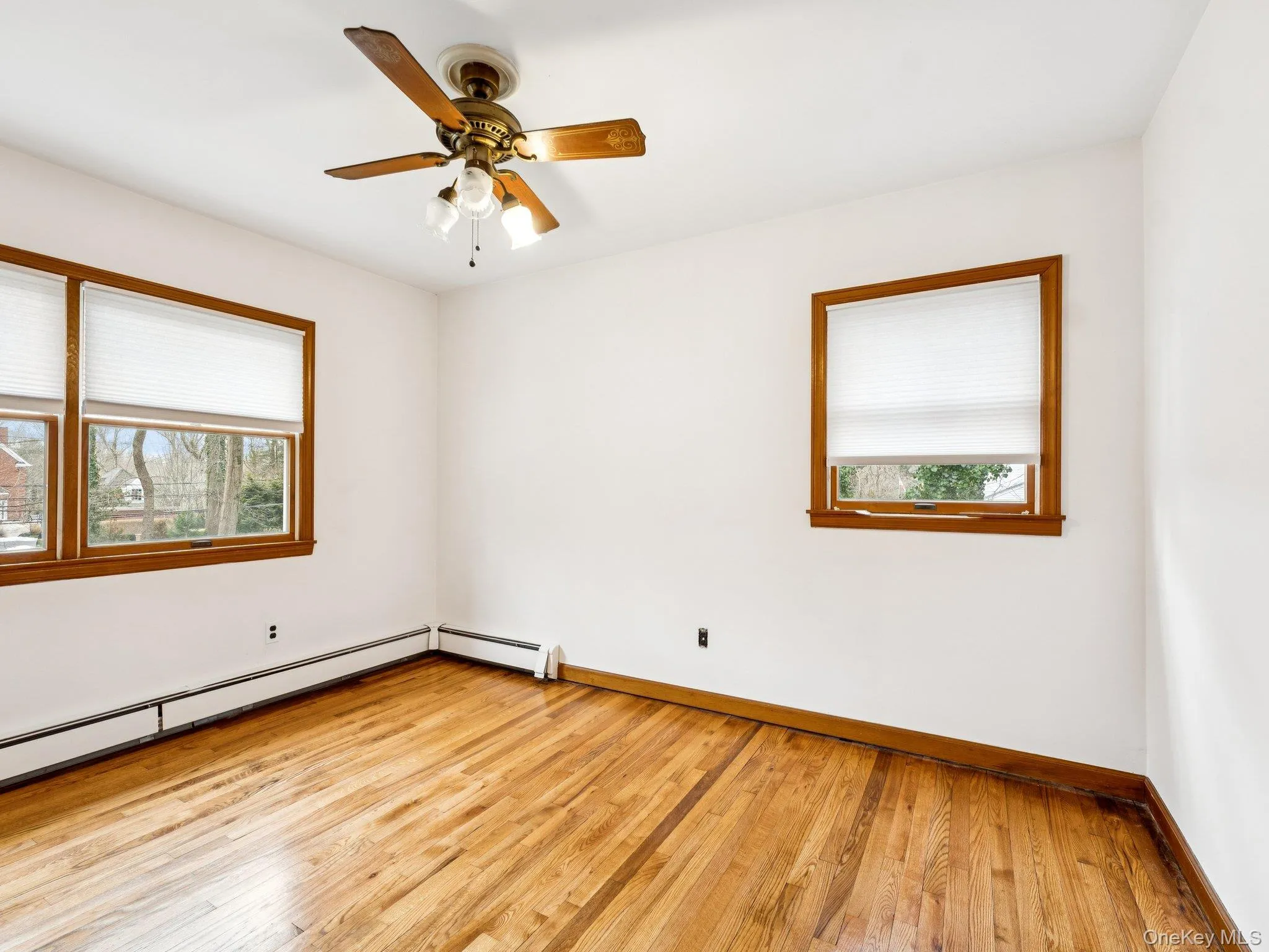 Empty room with plenty of natural light, light wood-type flooring, and a ceiling fan Empty room with plenty of natural light, light wood-type flooring, and a ceiling fan
