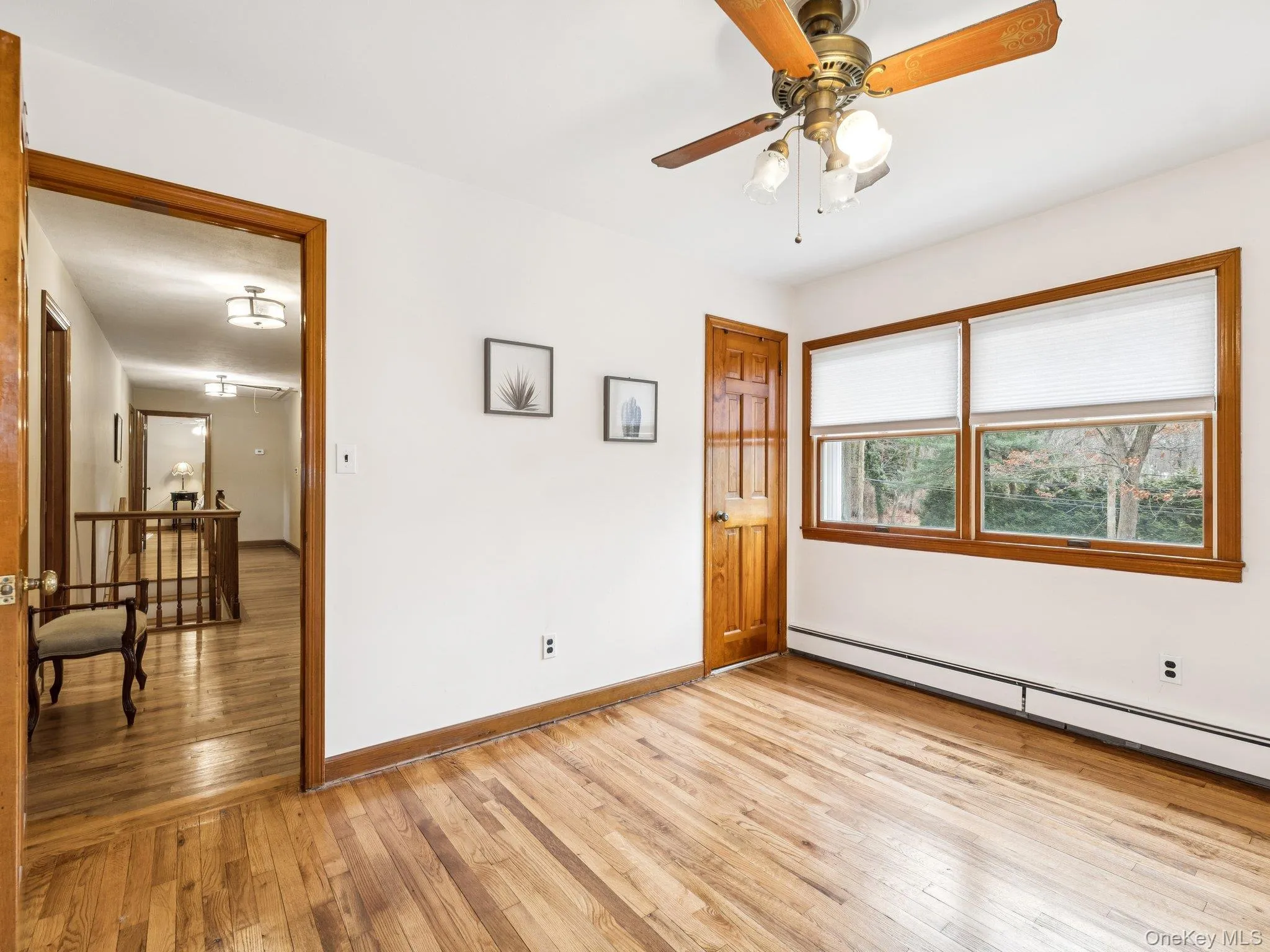 Unfurnished bedroom featuring light wood finished floors, a baseboard radiator, and ceiling fan Unfurnished bedroom featuring light wood finished floors, a baseboard radiator, and ceiling fan