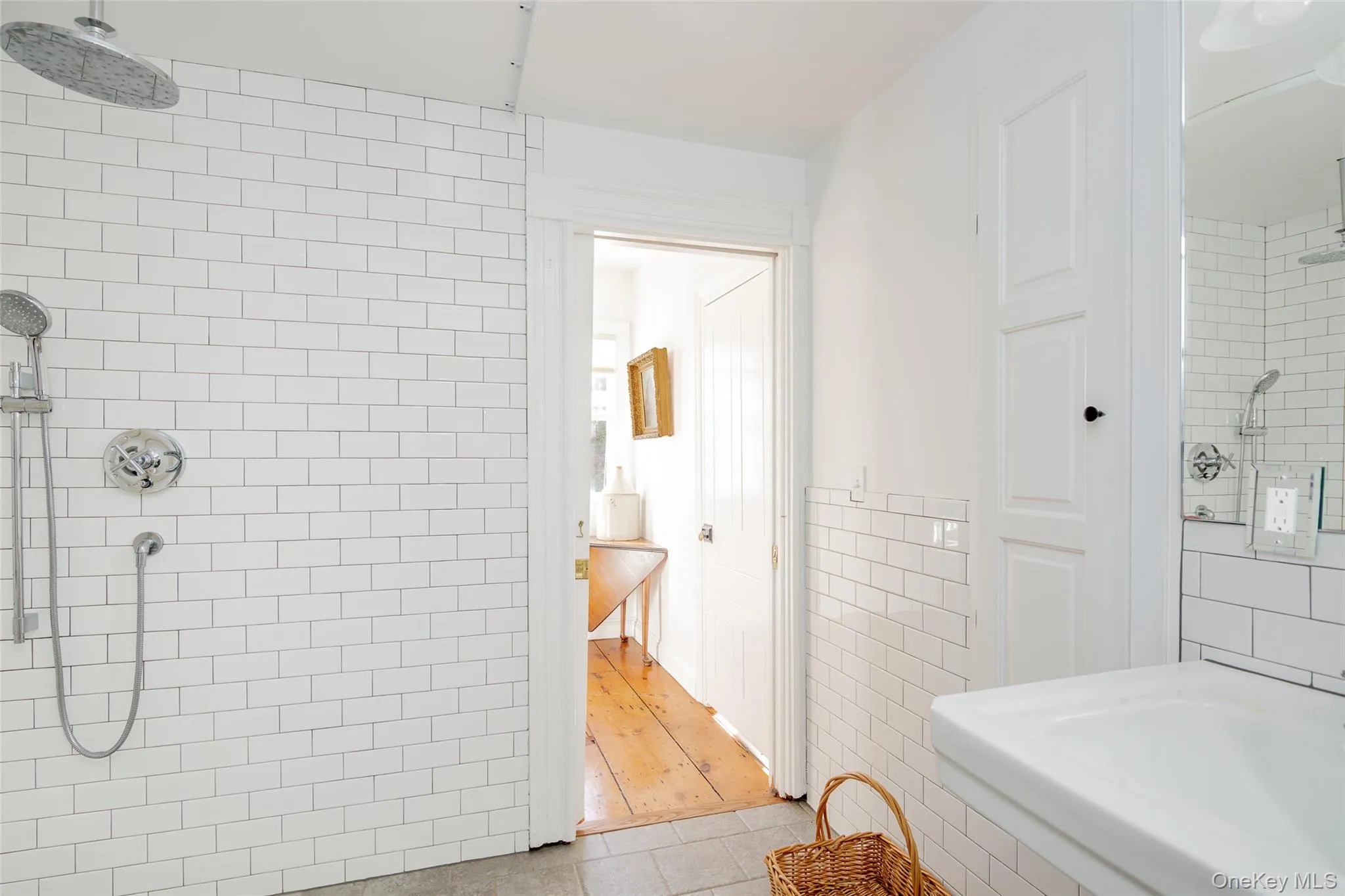 Bathroom with a tile shower, tile walls, light tile patterned floors, and a wainscoted wall Bathroom with a tile shower, tile walls, light tile patterned floors, and a wainscoted wall