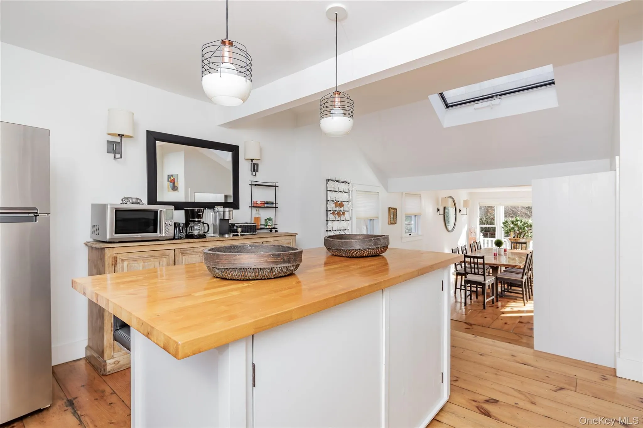 Kitchen featuring wood counters, a skylight, stainless steel appliances, hanging light fixtures, and light wood finished floors Kitchen featuring wood counters, a skylight, stainless steel appliances, hanging light fixtures, and light wood finished floors