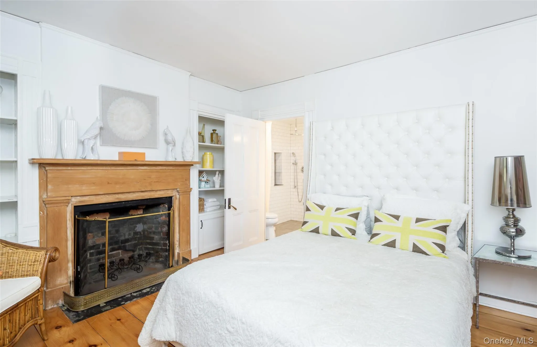 Bedroom featuring light wood finished floors, a fireplace, and ensuite bathroom Bedroom featuring light wood finished floors, a fireplace, and ensuite bathroom