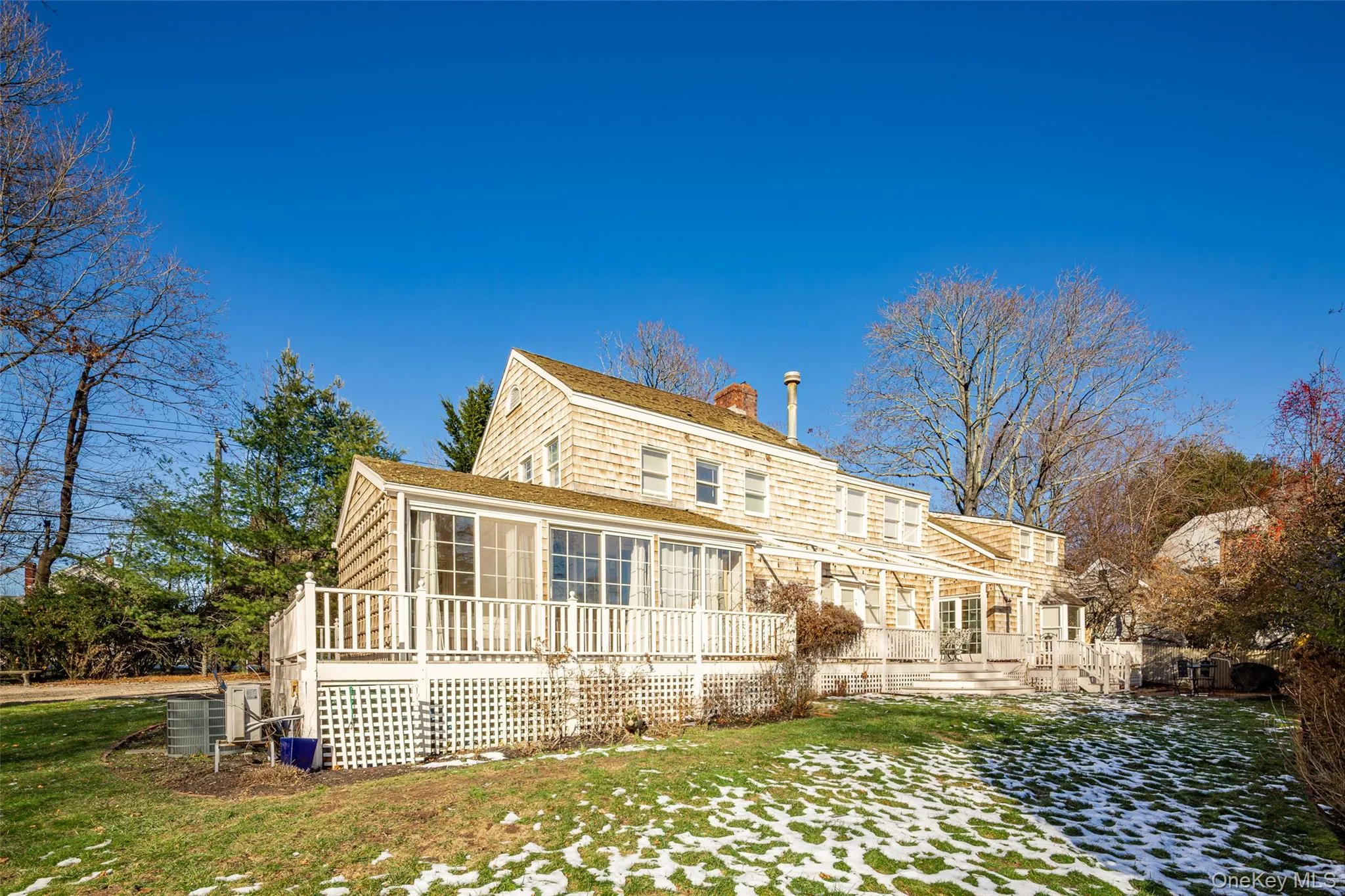 Back of property with a chimney, a sunroom, a deck, and a yard Back of property with a chimney, a sunroom, a deck, and a yard