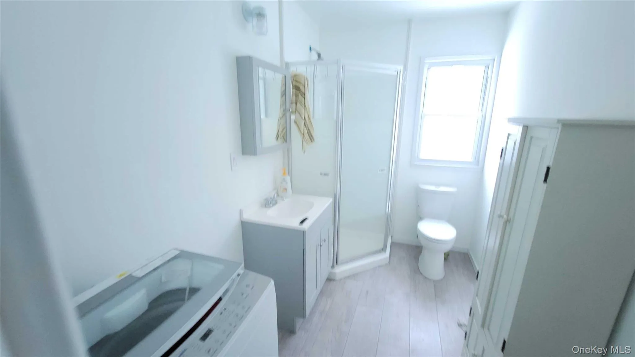 Full bath featuring vanity, a stall shower, and washer / dryer Full bath featuring vanity, a stall shower, and washer / dryer