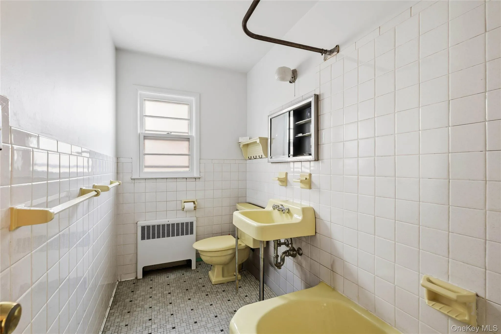 Full bathroom featuring a bath, radiator, tile walls, light tile patterned floors, and wainscoting Full bathroom featuring a bath, radiator, tile walls, light tile patterned floors, and wainscoting