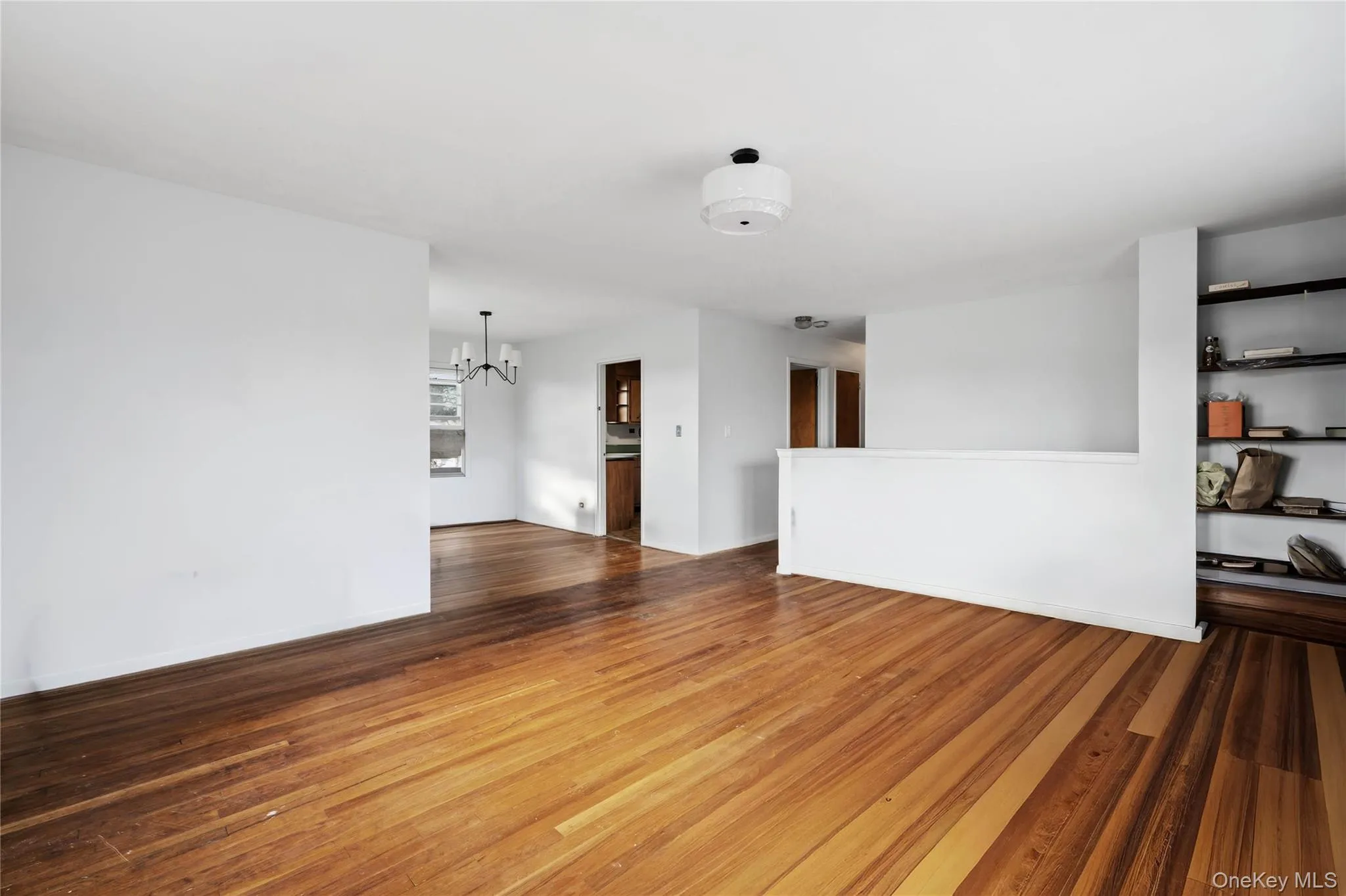 Unfurnished living room with dark wood-style floors and a chandelier Unfurnished living room with dark wood-style floors and a chandelier
