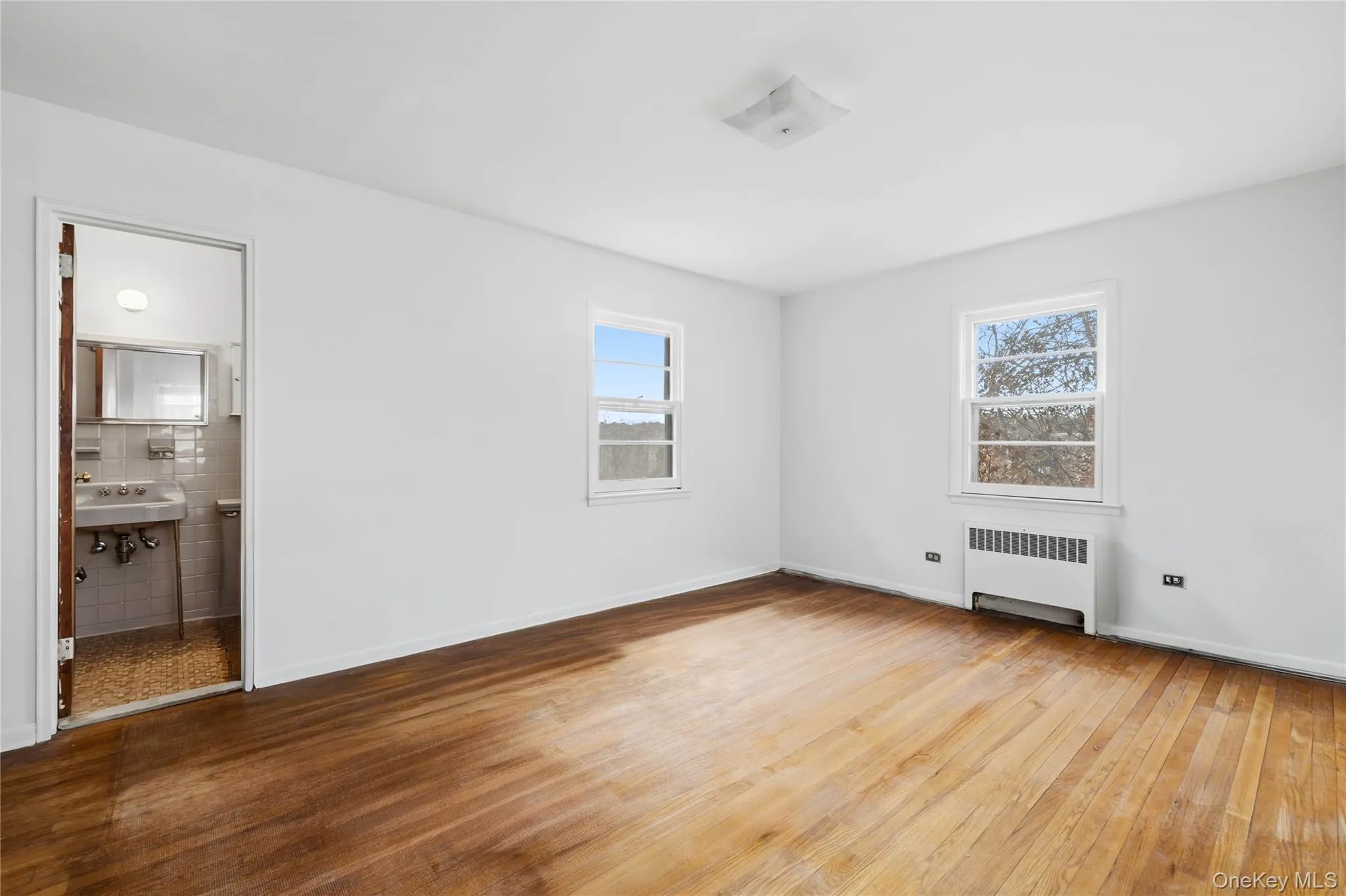 Unfurnished bedroom featuring light wood-style flooring and radiator heating unit Unfurnished bedroom featuring light wood-style flooring and radiator heating unit