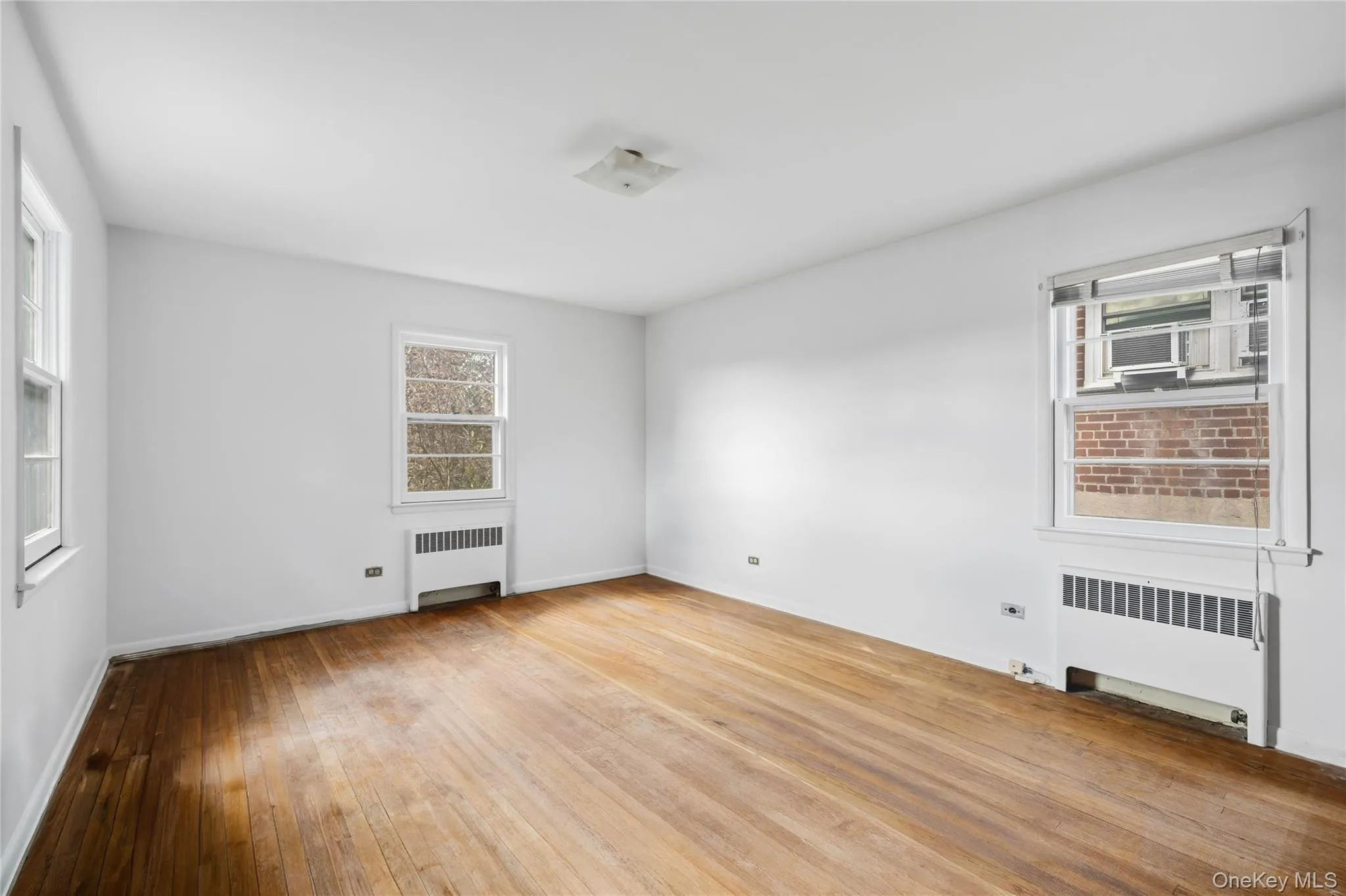 Empty room with radiator heating unit and light wood finished floors Empty room with radiator heating unit and light wood finished floors