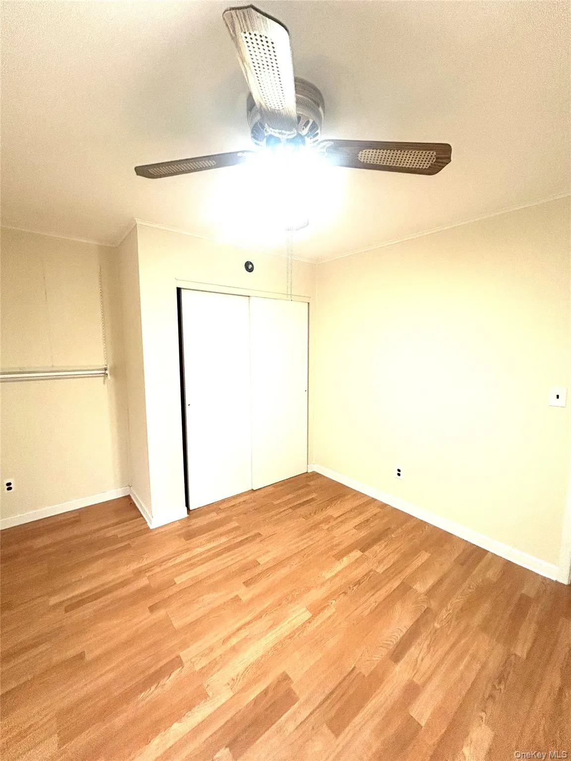 Unfurnished bedroom featuring a ceiling fan, light wood-style floors, a closet, and a textured ceiling Unfurnished bedroom featuring a ceiling fan, light wood-style floors, a closet, and a textured ceiling