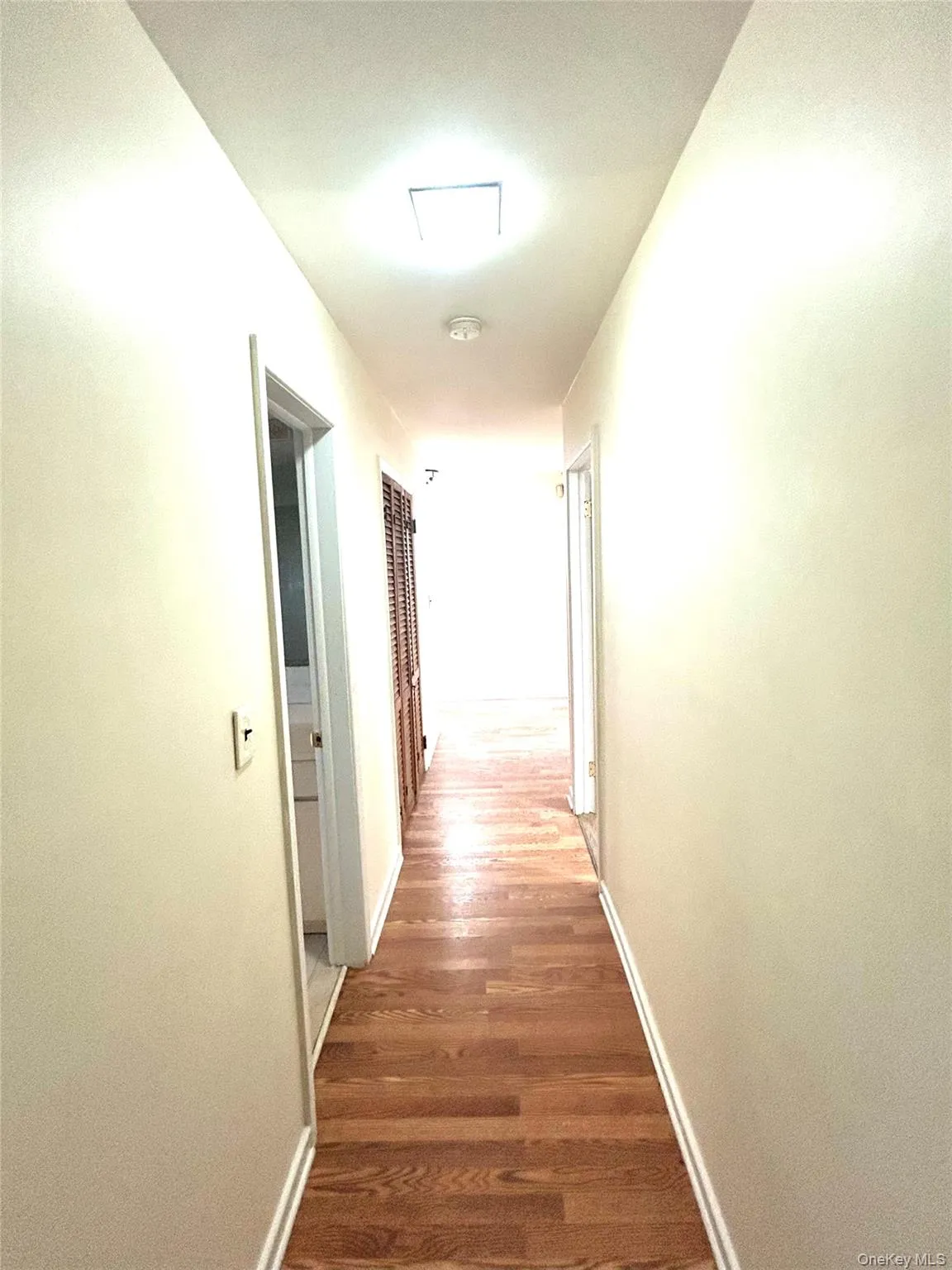 Corridor with dark wood-style floors and baseboards Corridor with dark wood-style floors and baseboards