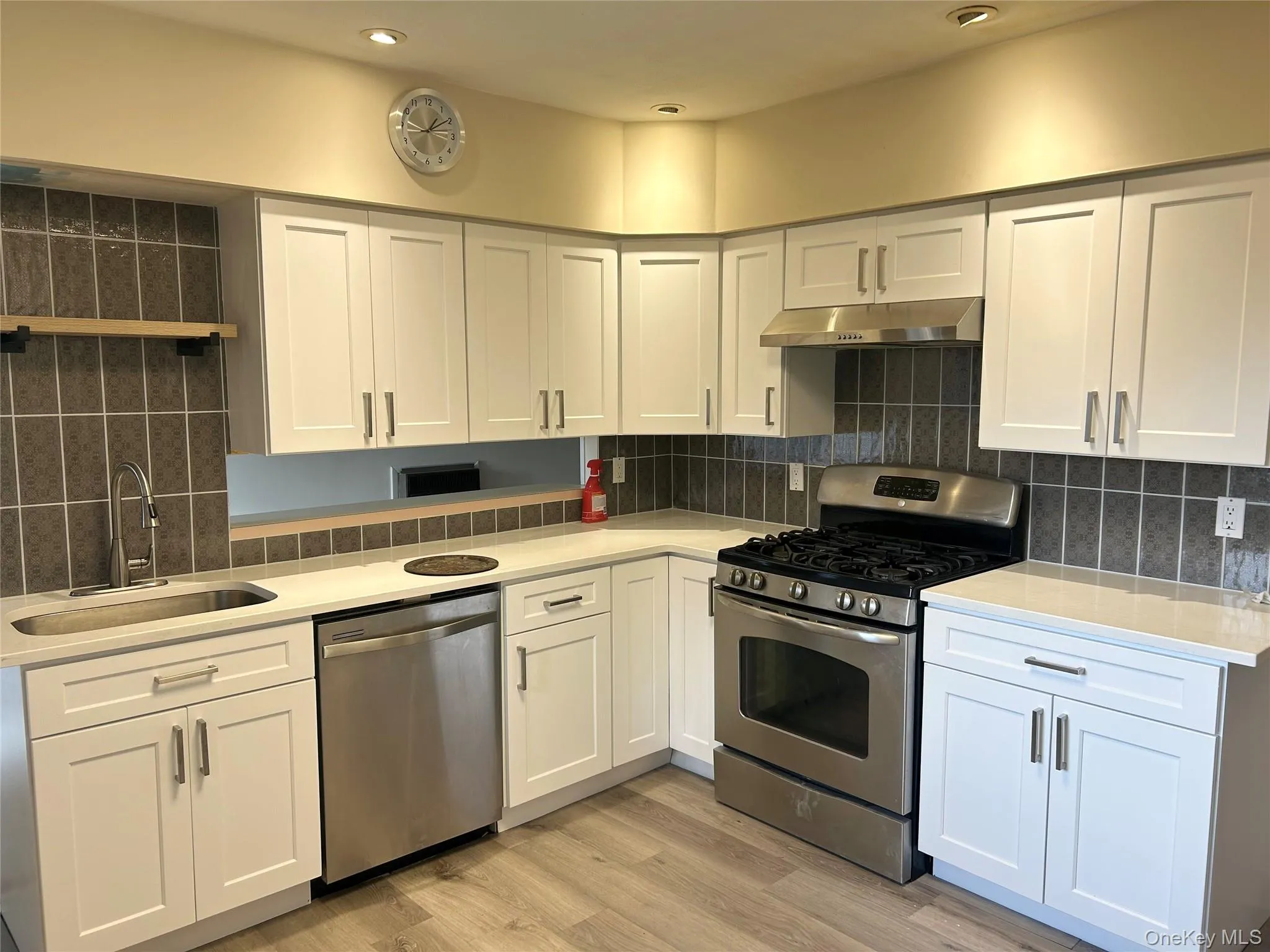 Kitchen featuring stainless steel appliances, white cabinets, light wood-style floors, and open shelves Kitchen featuring stainless steel appliances, white cabinets, light wood-style floors, and open shelves