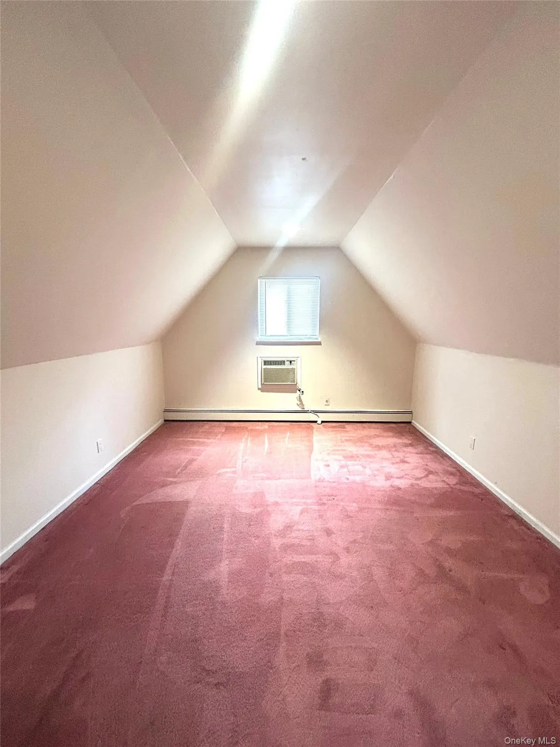 Additional living space with carpet floors, lofted ceiling, a wall unit AC, and a baseboard radiator Additional living space with carpet floors, lofted ceiling, a wall unit AC, and a baseboard radiator