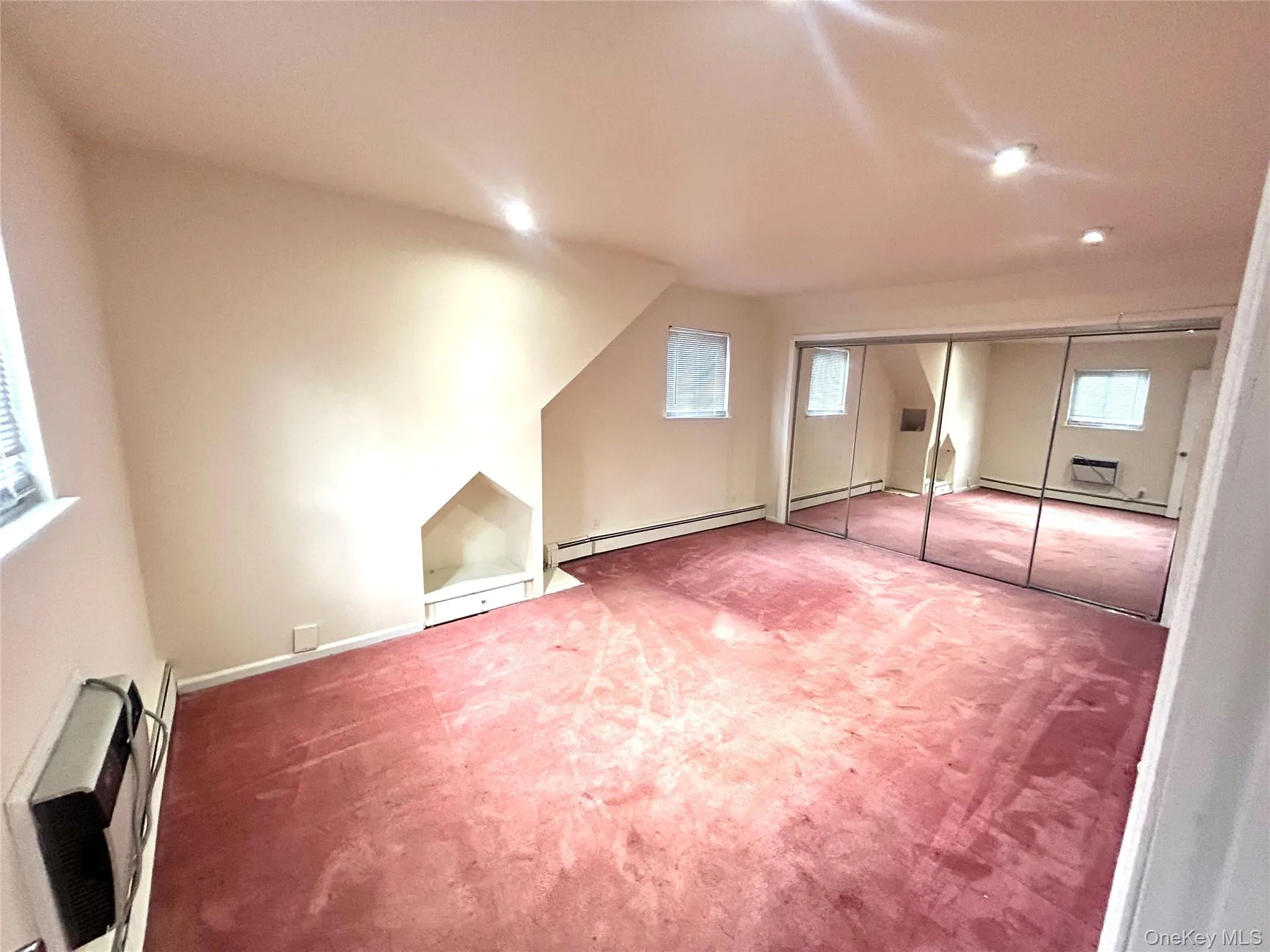 Additional living space featuring heating unit, carpet, baseboard heating, and an AC wall unit Additional living space featuring heating unit, carpet, baseboard heating, and an AC wall unit