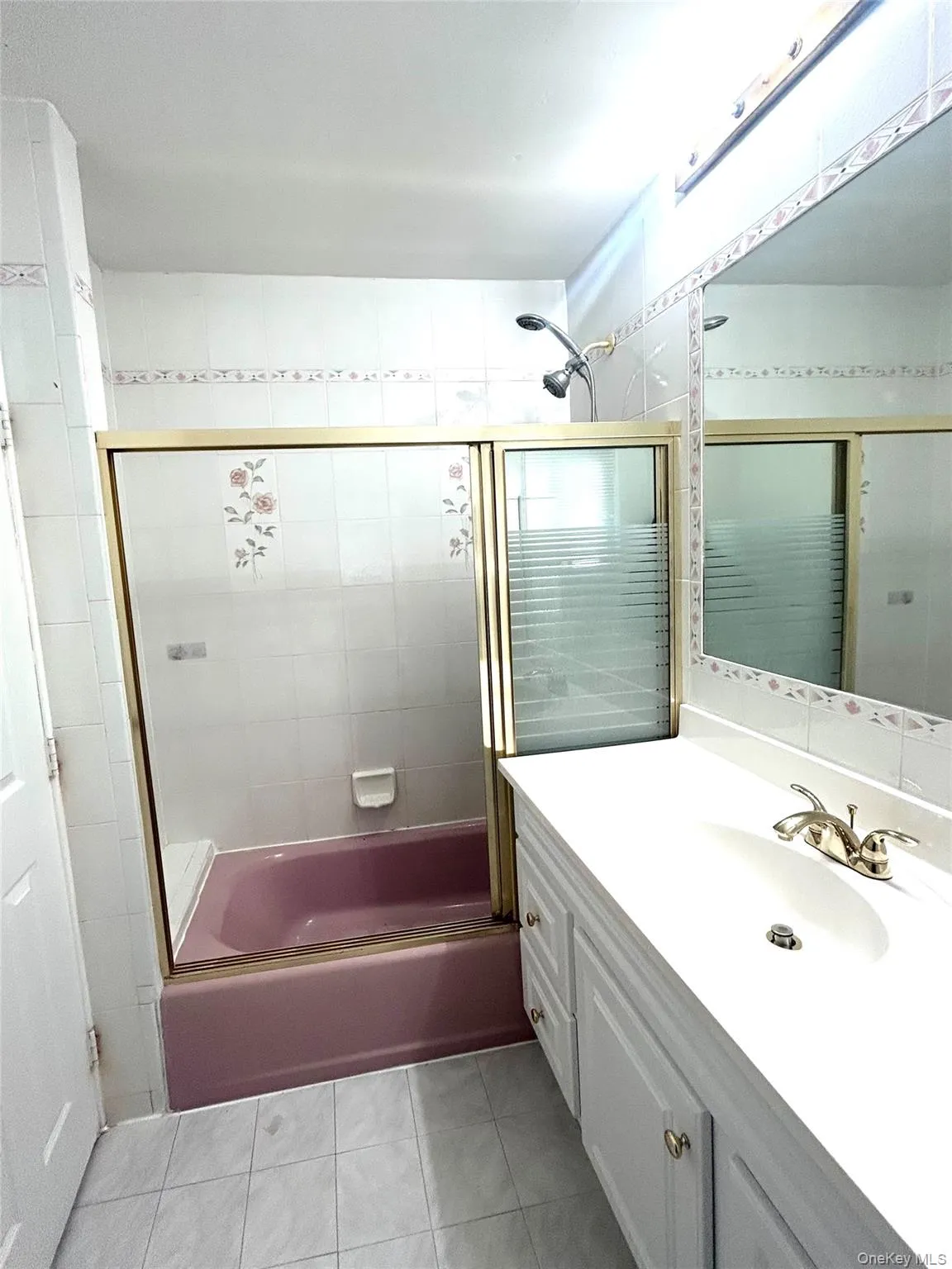 Full bathroom featuring enclosed tub / shower combo, vanity, and light tile patterned floors Full bathroom featuring enclosed tub / shower combo, vanity, and light tile patterned floors