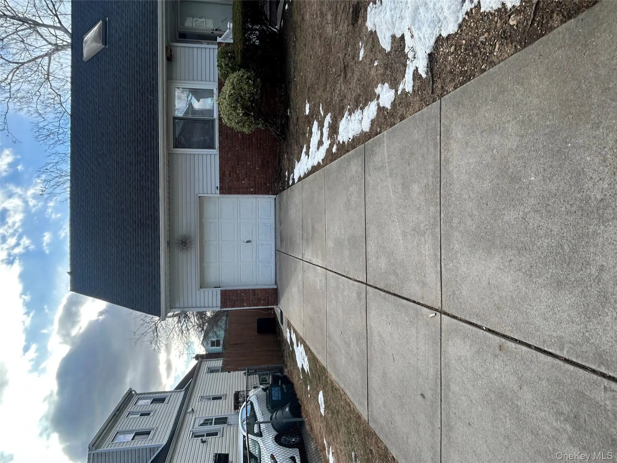 View of side of home featuring brick siding, concrete driveway, a garage, and a shingled roof View of side of home featuring brick siding, concrete driveway, a garage, and a shingled roof