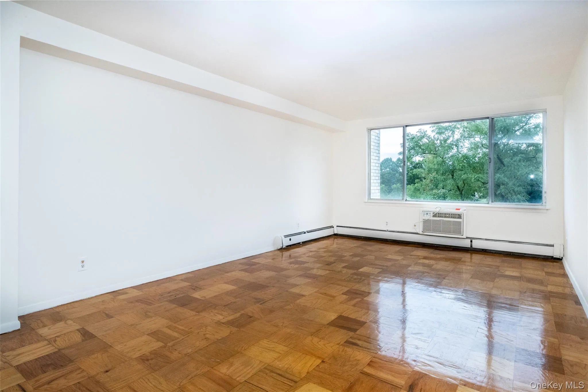 Empty room featuring baseboard heating and a wall mounted air conditioner Empty room featuring baseboard heating and a wall mounted air conditioner