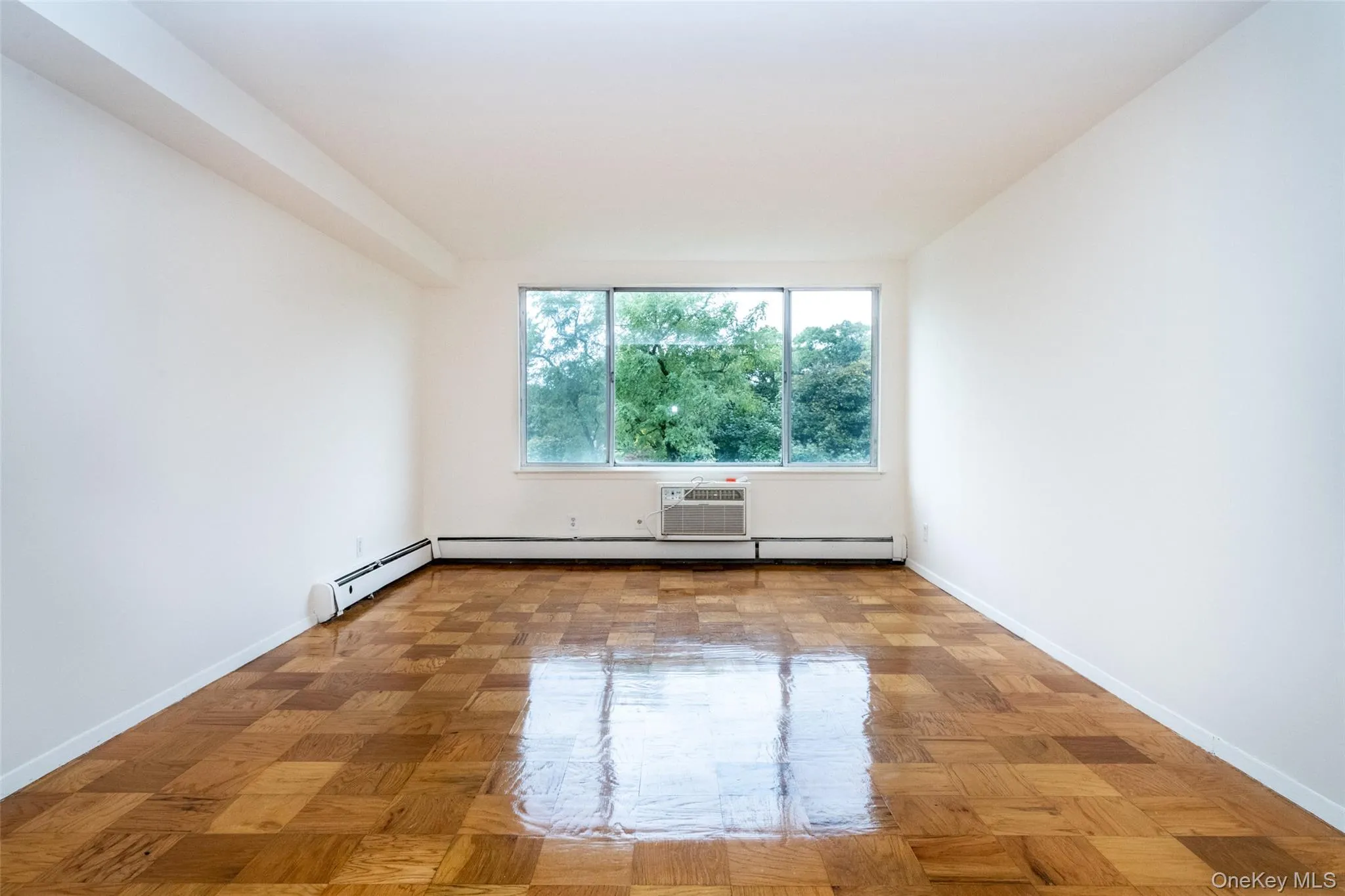 Unfurnished room featuring baseboard heating and an AC wall unit Unfurnished room featuring baseboard heating and an AC wall unit