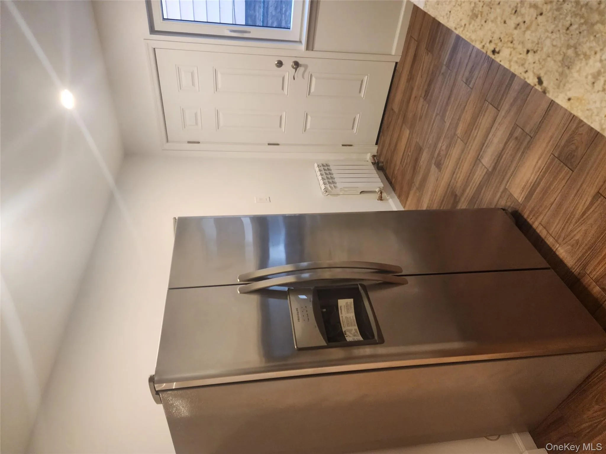 Kitchen with stainless steel fridge with ice dispenser, dark wood-style flooring, radiator, and recessed lighting Kitchen with stainless steel fridge with ice dispenser, dark wood-style flooring, radiator, and recessed lighting