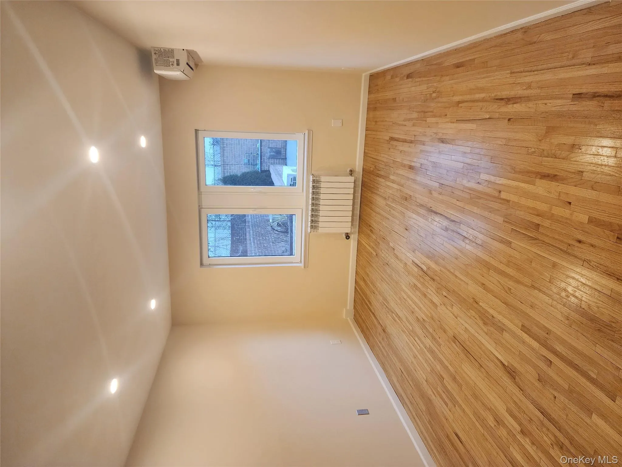 Spare room with recessed lighting, light wood-type flooring, radiator, and a wall unit AC Spare room with recessed lighting, light wood-type flooring, radiator, and a wall unit AC