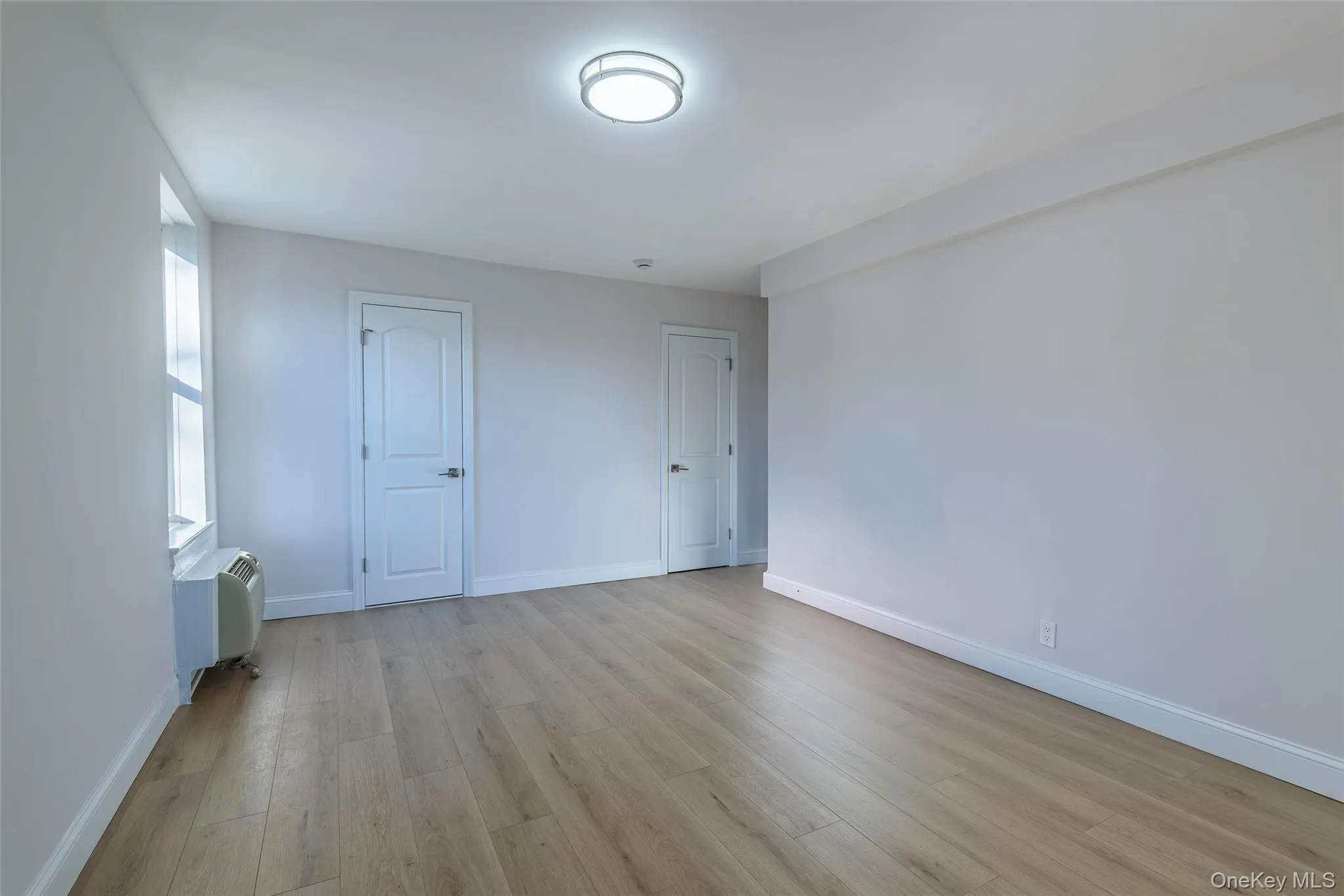Unfurnished bedroom with light wood finished floors and baseboards Unfurnished bedroom with light wood finished floors and baseboards