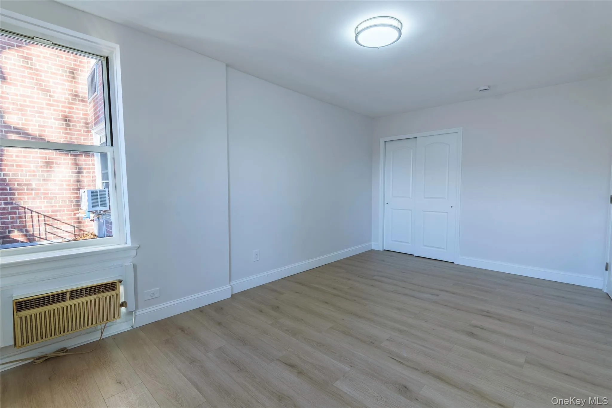 Unfurnished room with light wood-type flooring and a wall mounted air conditioner Unfurnished room with light wood-type flooring and a wall mounted air conditioner