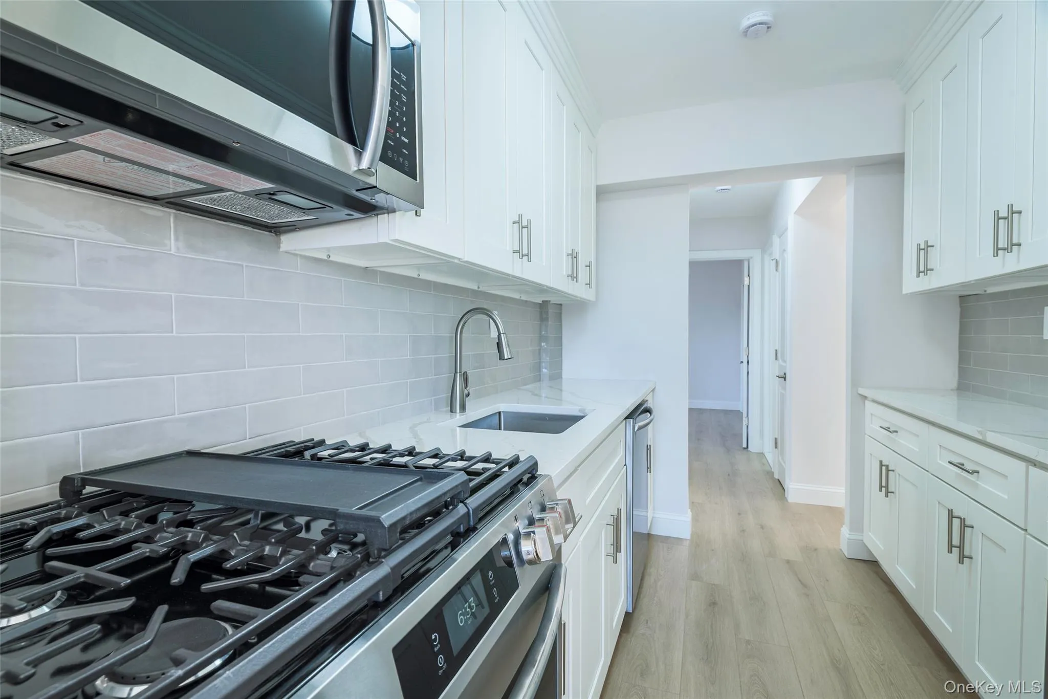 Kitchen featuring appliances with stainless steel finishes, light stone countertops, white cabinets, and tasteful backsplash Kitchen featuring appliances with stainless steel finishes, light stone countertops, white cabinets, and tasteful backsplash