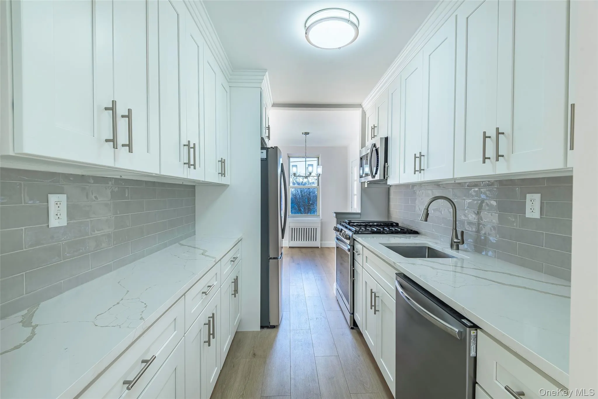 Kitchen featuring light stone counters, stainless steel appliances, and white cabinetry Kitchen featuring light stone counters, stainless steel appliances, and white cabinetry