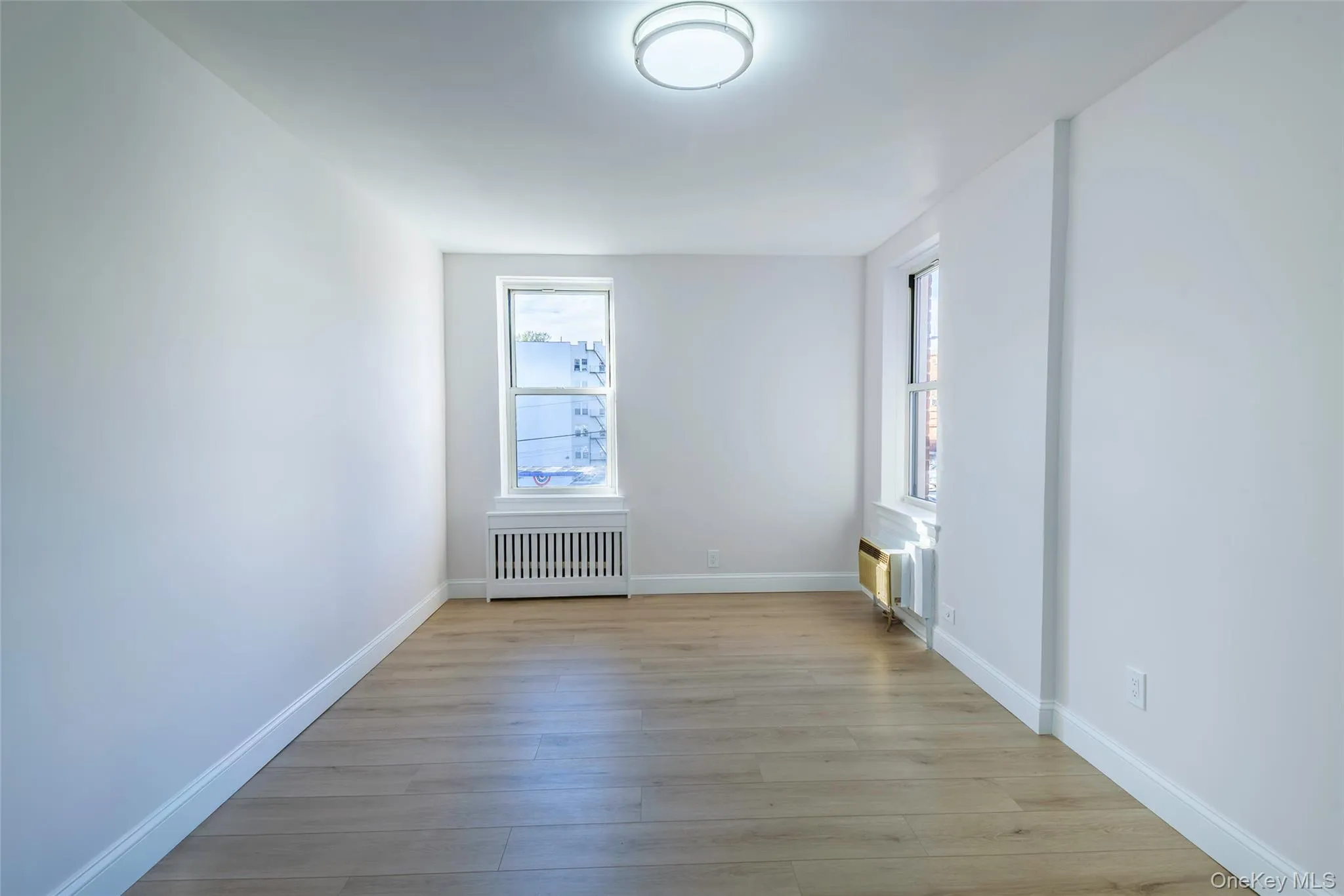 Unfurnished room featuring light wood-type flooring and radiator Unfurnished room featuring light wood-type flooring and radiator
