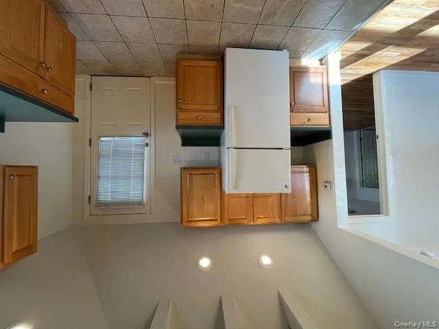 Kitchen with vaulted ceiling, fridge, dark countertops, recessed lighting, and light tile patterned floors Kitchen with vaulted ceiling, fridge, dark countertops, recessed lighting, and light tile patterned floors