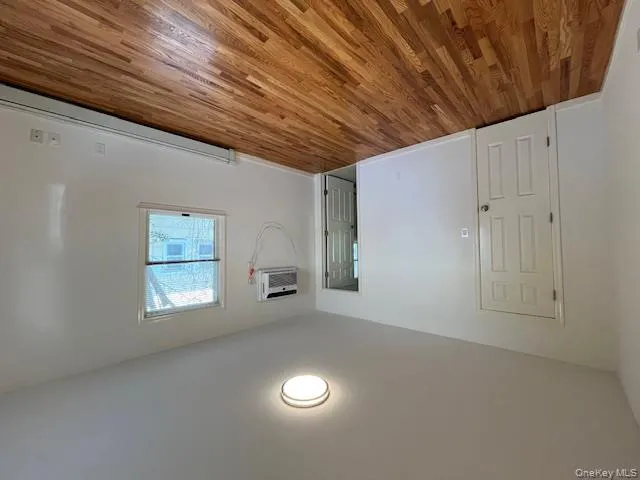 Unfurnished bedroom featuring light wood-style floors, a baseboard radiator, and a wall unit AC Unfurnished bedroom featuring light wood-style floors, a baseboard radiator, and a wall unit AC