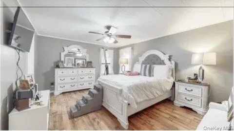 Bedroom featuring ceiling fan and light wood-style flooring Bedroom featuring ceiling fan and light wood-style flooring