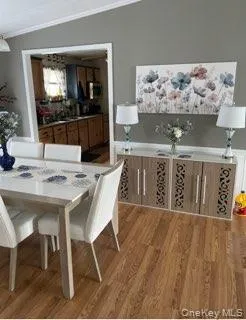 Dining space featuring light wood-style flooring, lofted ceiling, and ornamental molding Dining space featuring light wood-style flooring, lofted ceiling, and ornamental molding