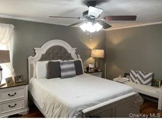 Bedroom with crown molding, dark wood finished floors, and a ceiling fan Bedroom with crown molding, dark wood finished floors, and a ceiling fan