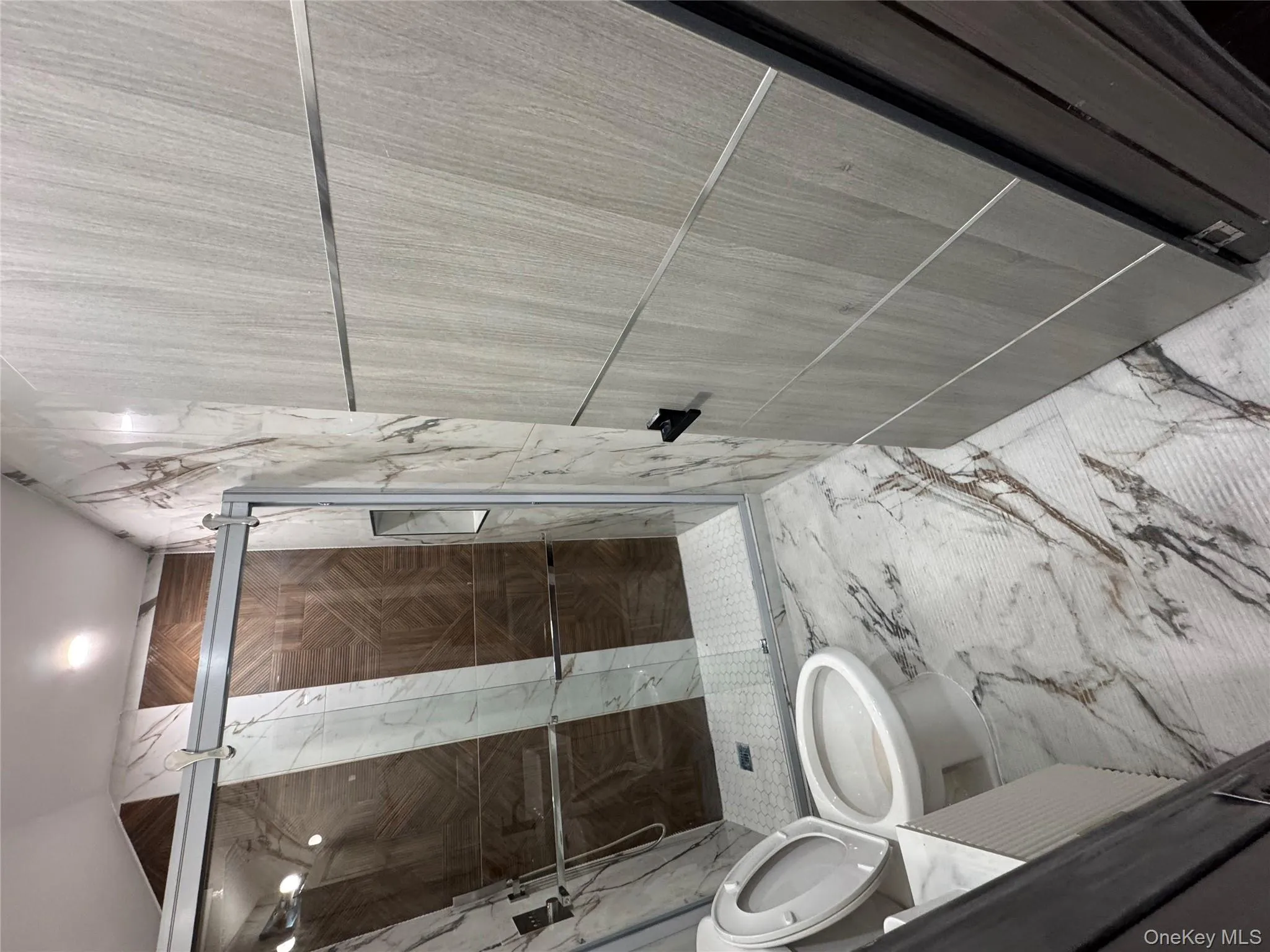 Bathroom with marble tiled floors, a marble finish shower, vanity, and tile walls Bathroom with marble tiled floors, a marble finish shower, vanity, and tile walls