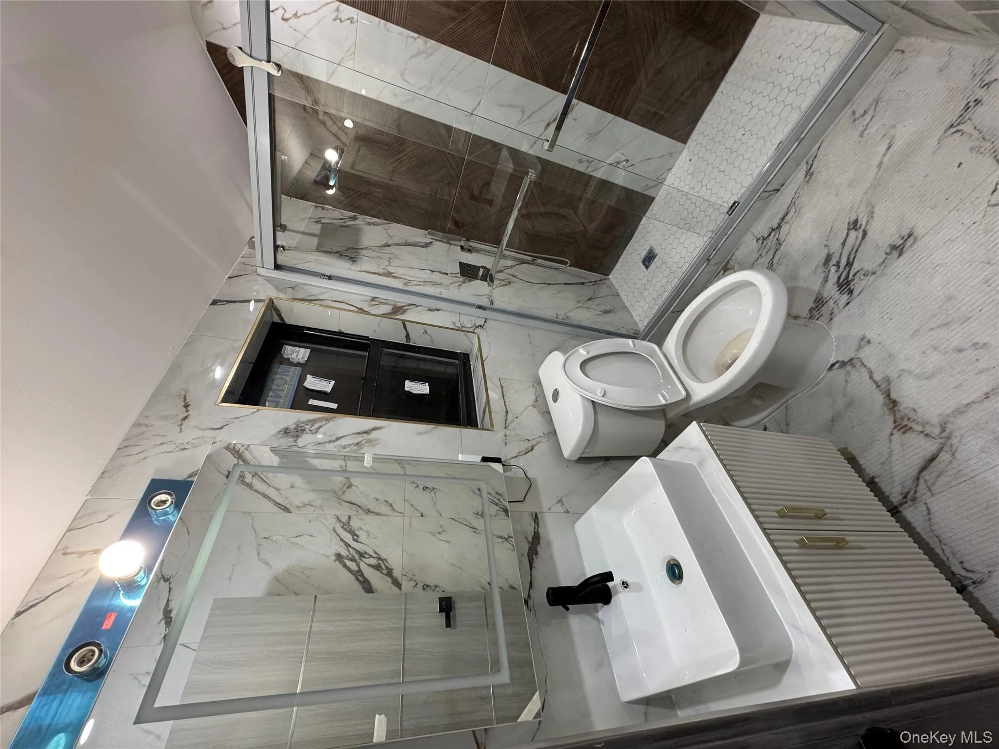 Full bath featuring stone wall, tile walls, marble tiled floors, a marble finish shower, and vanity Full bath featuring stone wall, tile walls, marble tiled floors, a marble finish shower, and vanity
