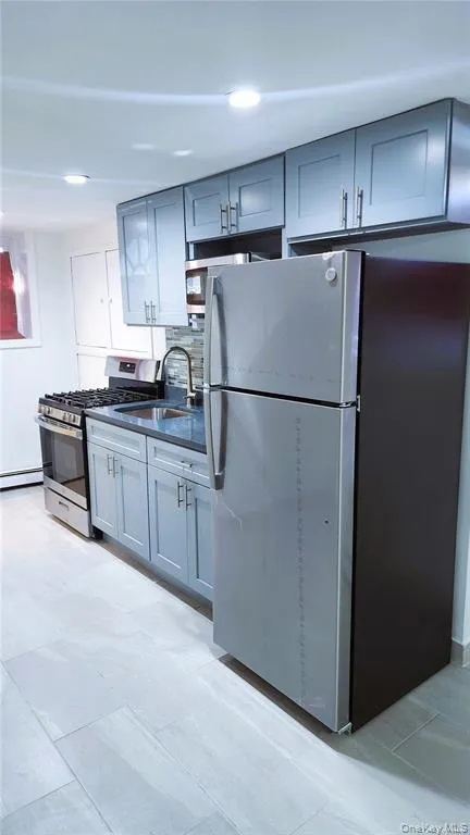 Kitchen with stainless steel appliances, dark countertops, gray cabinets, recessed lighting, and baseboard heating Kitchen with stainless steel appliances, dark countertops, gray cabinets, recessed lighting, and baseboard heating