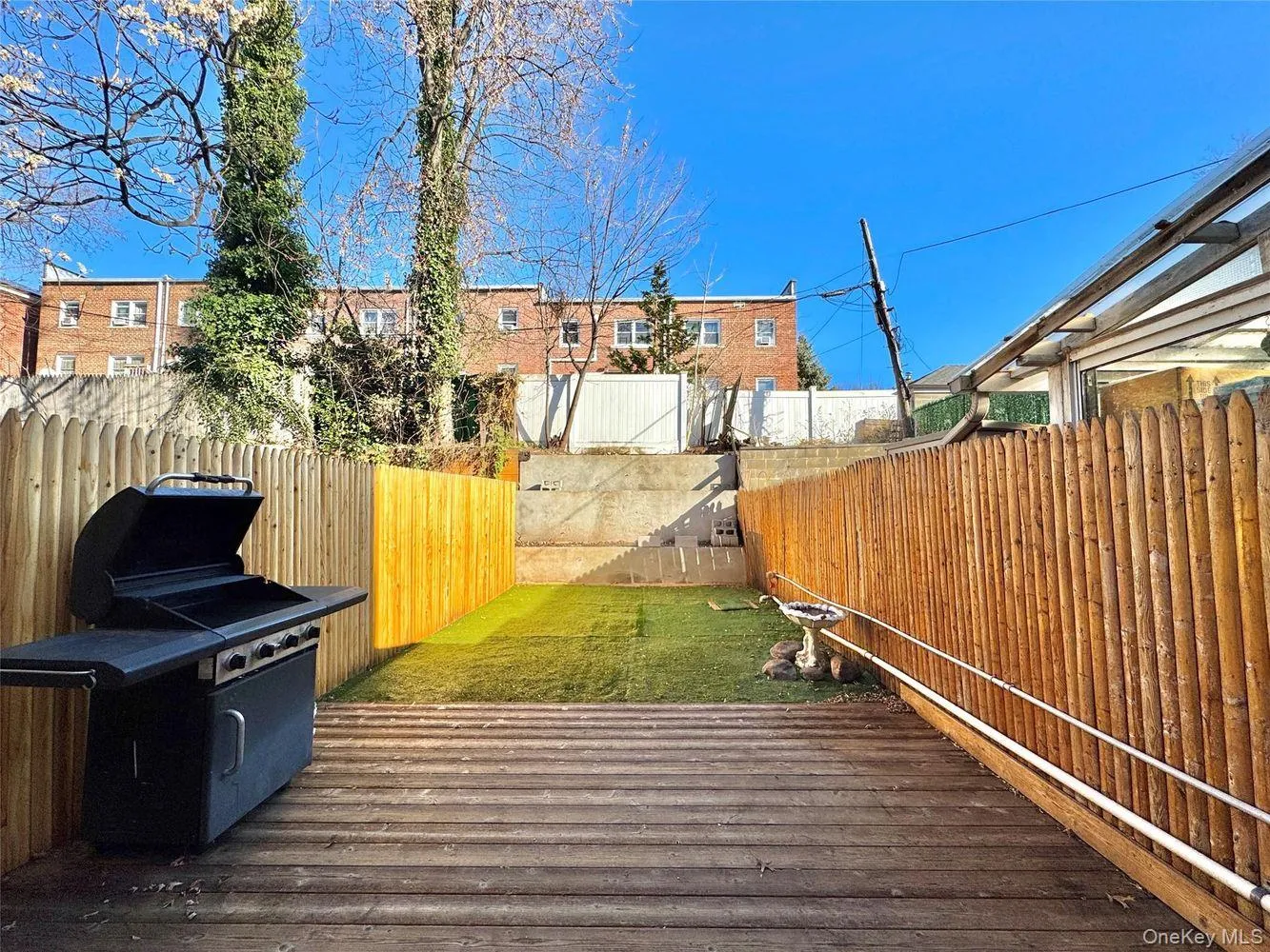 Wooden terrace with a fenced backyard and a grill Wooden terrace with a fenced backyard and a grill
