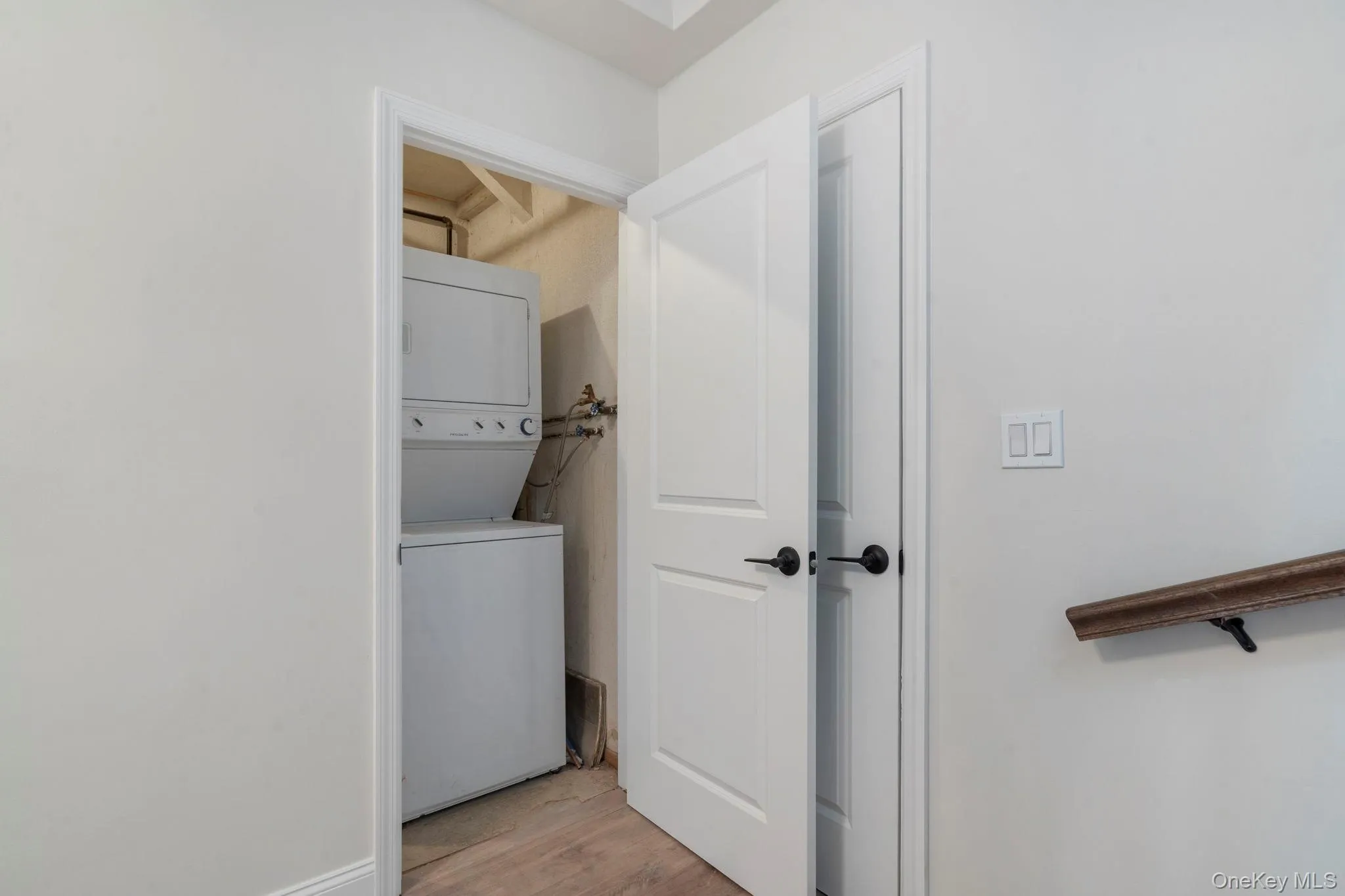 Laundry area featuring light wood-style floors and stacked washer / drying machine Laundry area featuring light wood-style floors and stacked washer / drying machine