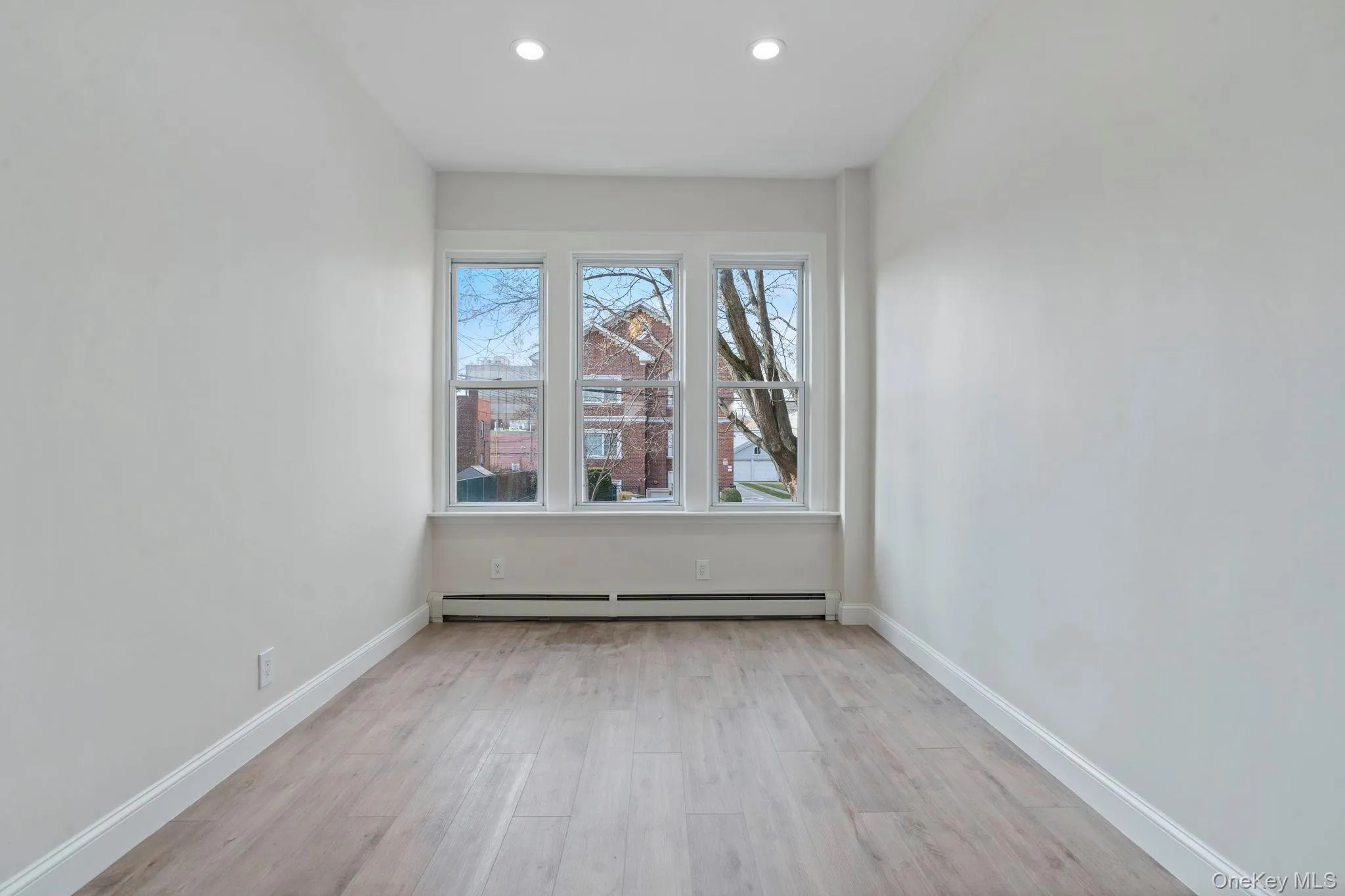 Unfurnished room featuring light wood finished floors, a baseboard radiator, and recessed lighting Unfurnished room featuring light wood finished floors, a baseboard radiator, and recessed lighting
