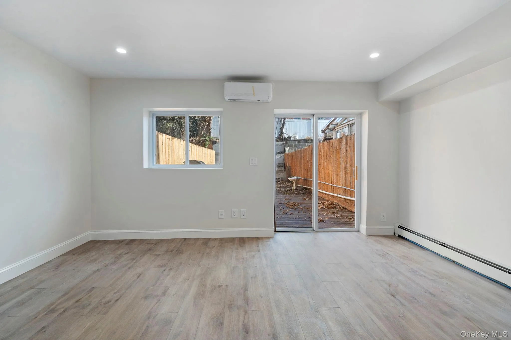 Unfurnished room featuring light wood-style floors, a wall mounted air conditioner, and recessed lighting Unfurnished room featuring light wood-style floors, a wall mounted air conditioner, and recessed lighting